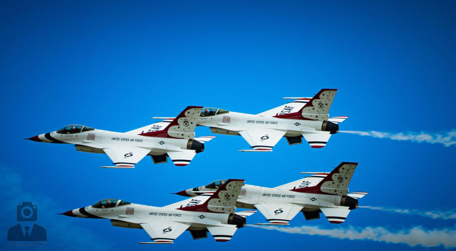 Four USAF Thunderbirds F-16 jets flying in tight diamond formation against a vivid blue sky at an airshow.