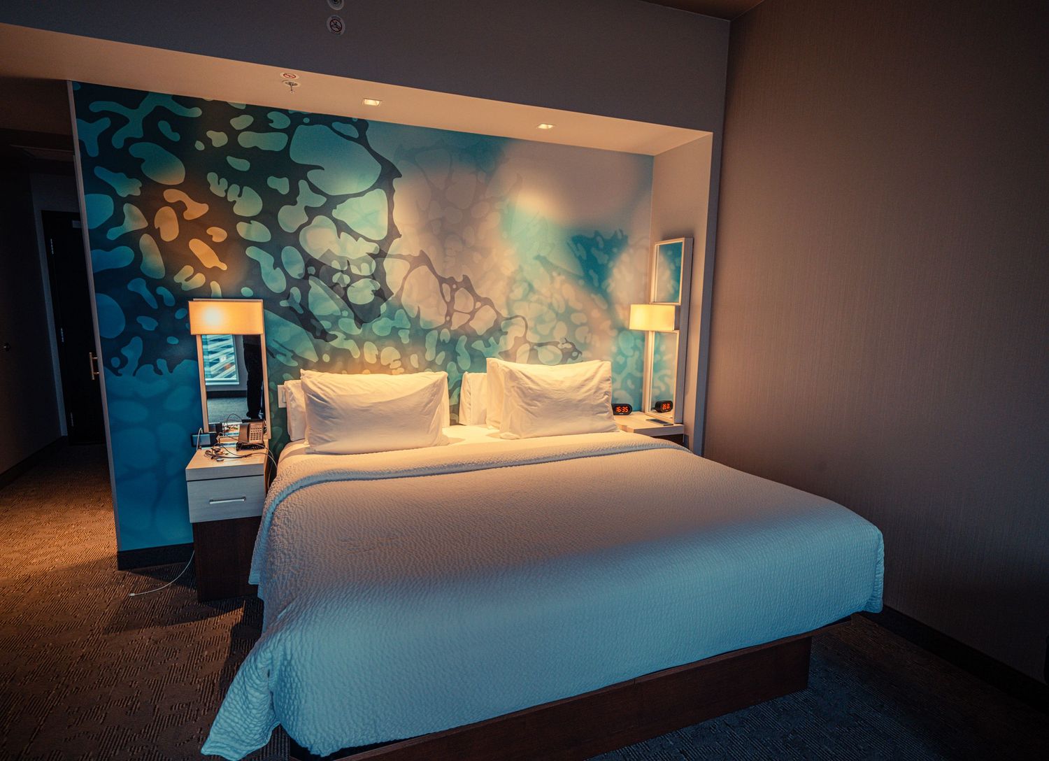 Modern hotel room with artistic headboard and ambient lighting.