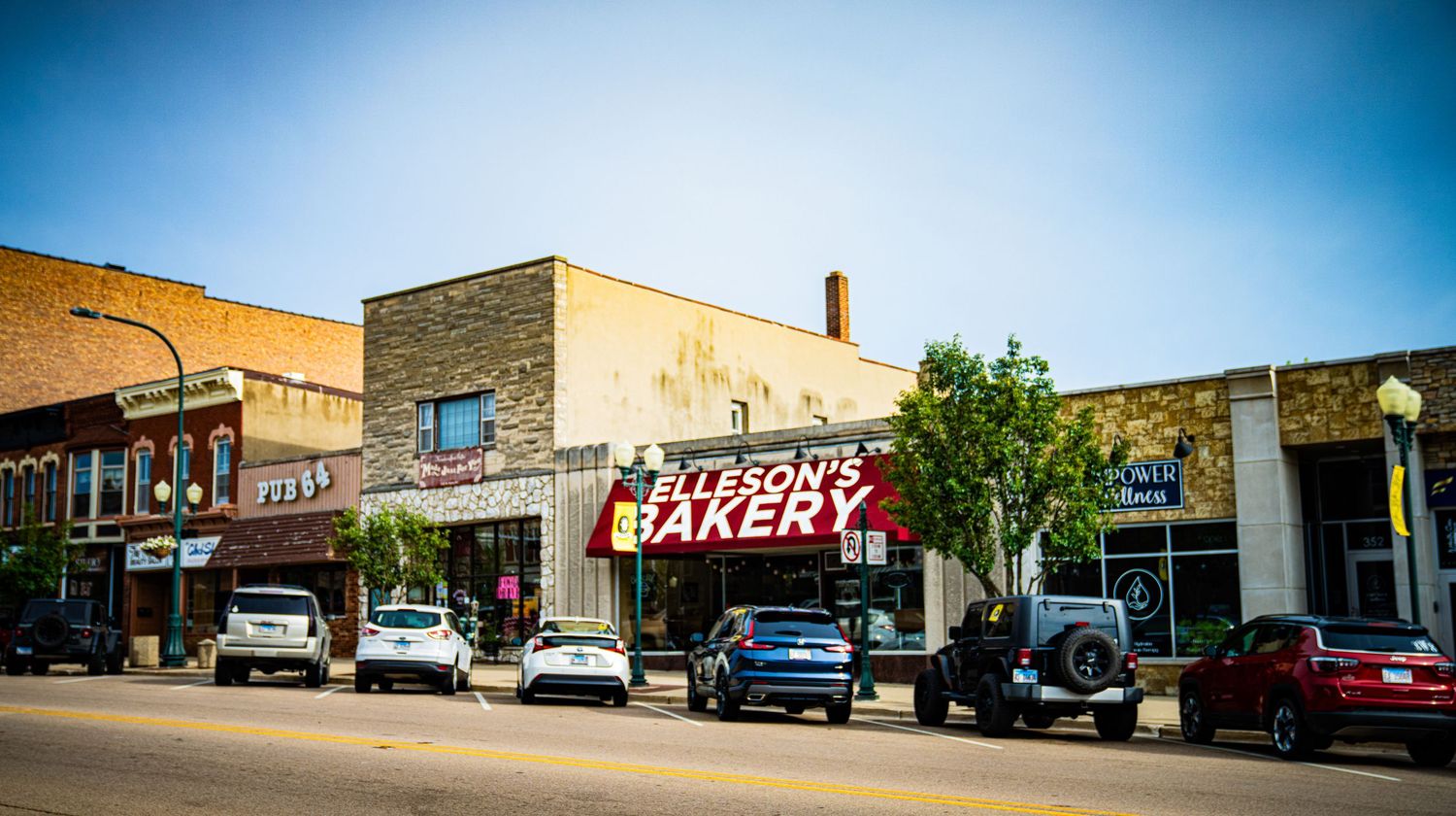 Row of commercial buildings and parked vehicles along a small town street.