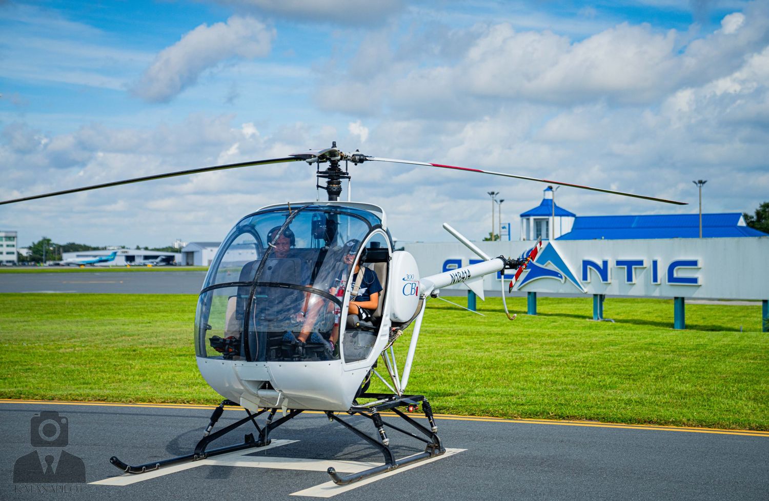 Helicopter landing pad area with multiple aircraft visible on grassy airfield.
