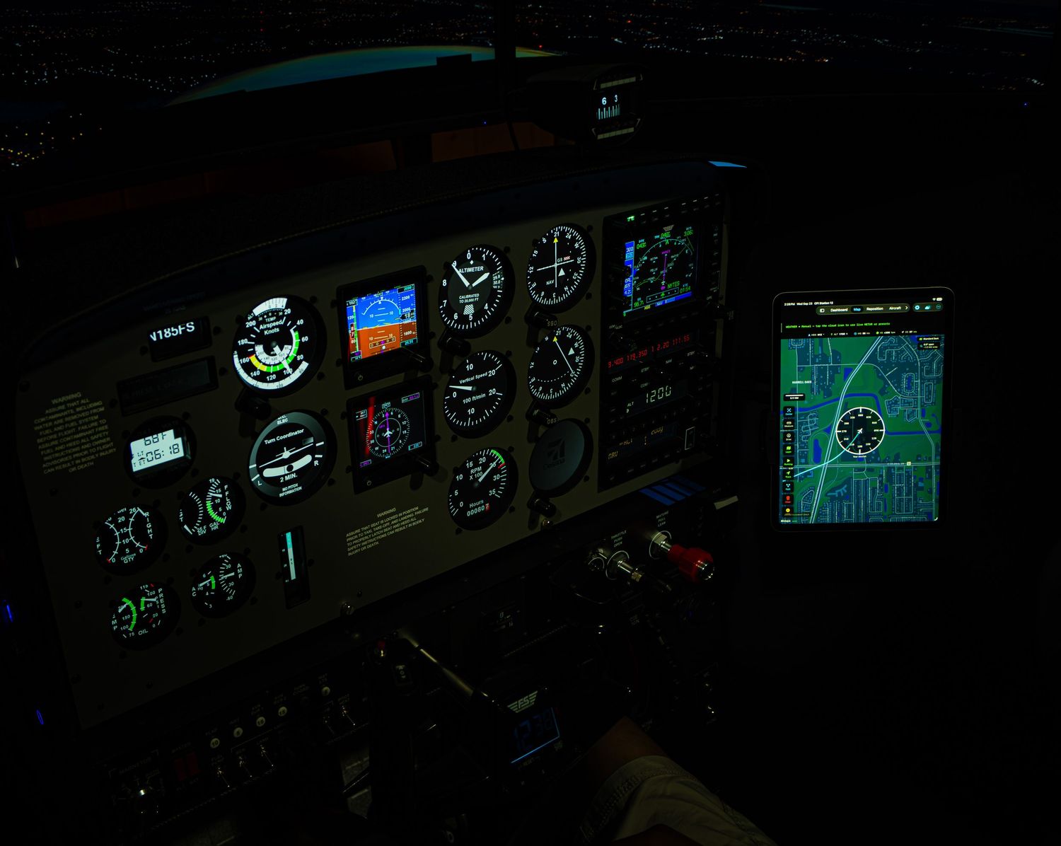 Illuminated aircraft cockpit instrument panel at night with glowing gauges and a GPS navigation display.