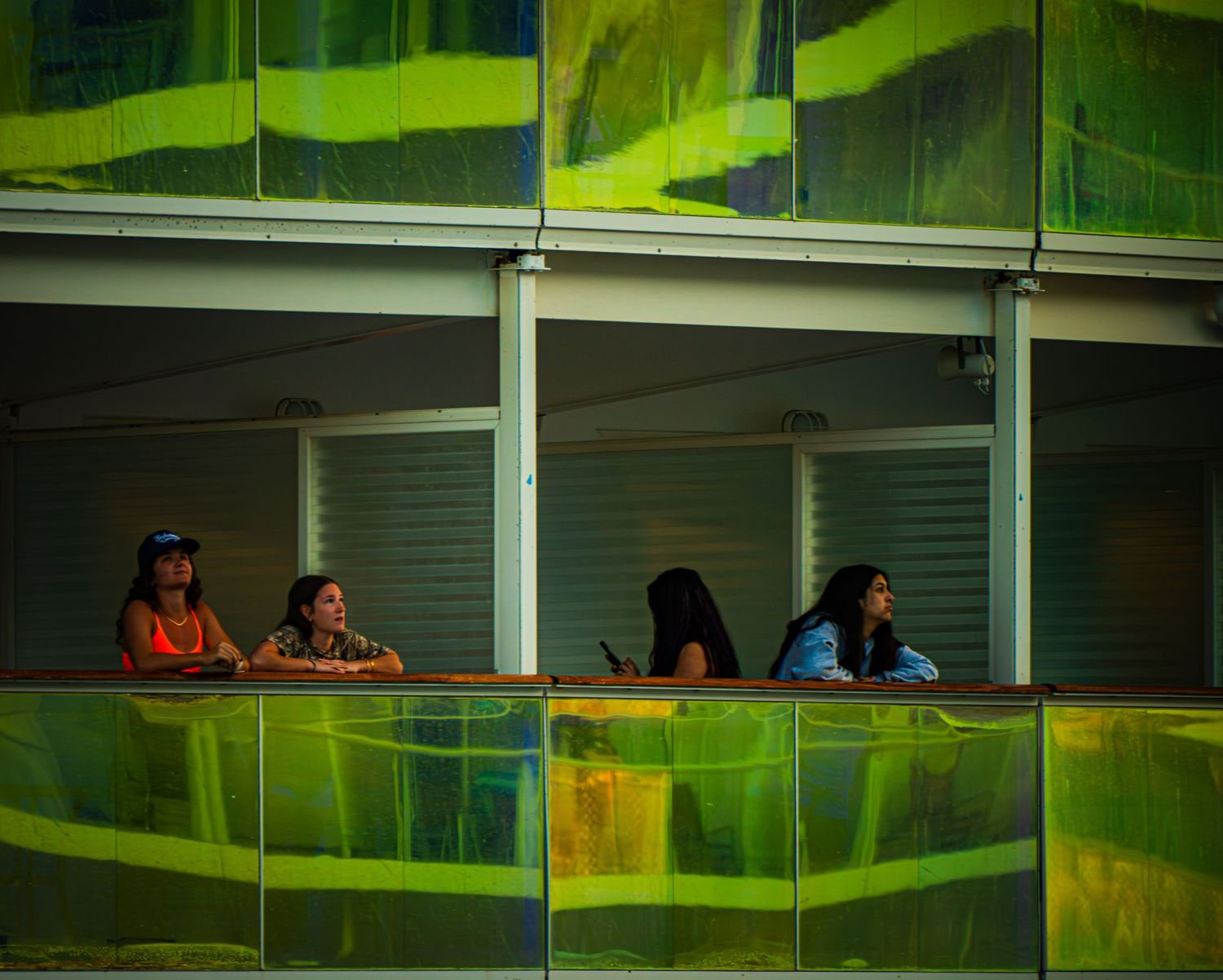 People sit under green awnings at a covered outdoor seating area.