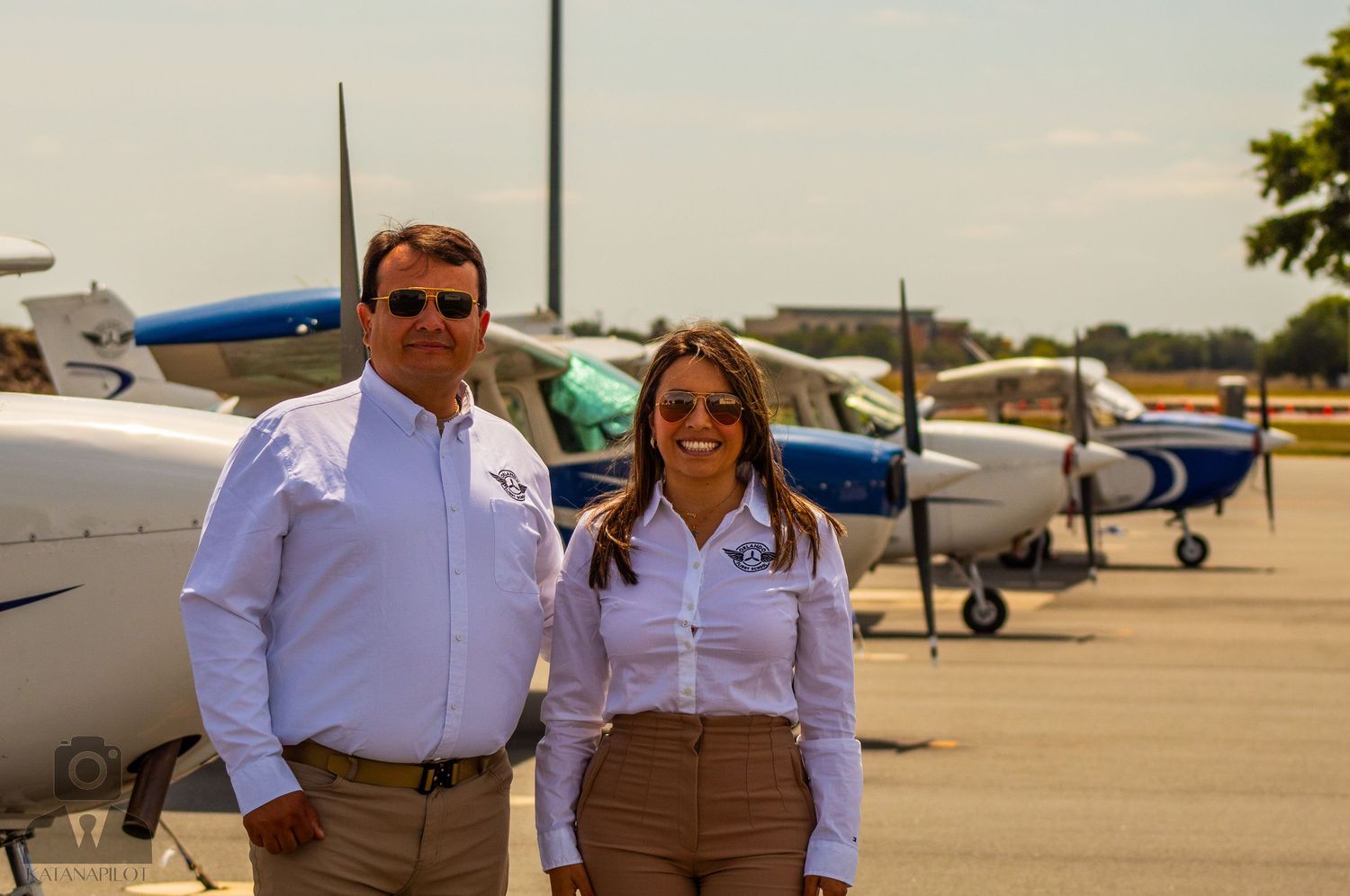 Group photo at airfield with aircraft visible in background.