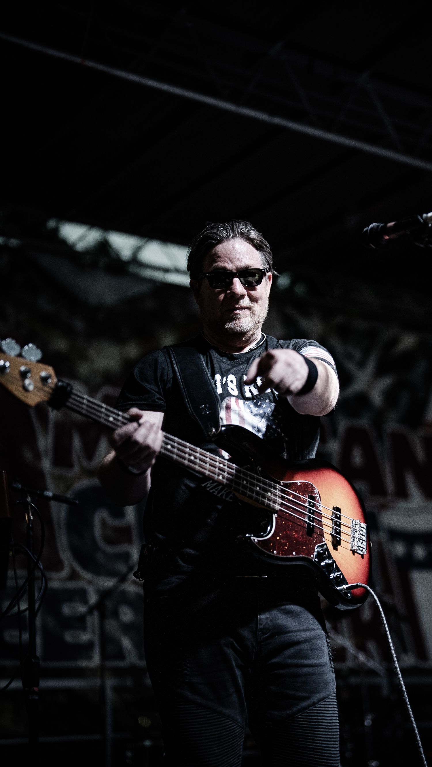 Musician playing bass guitar on stage in dramatic lighting.