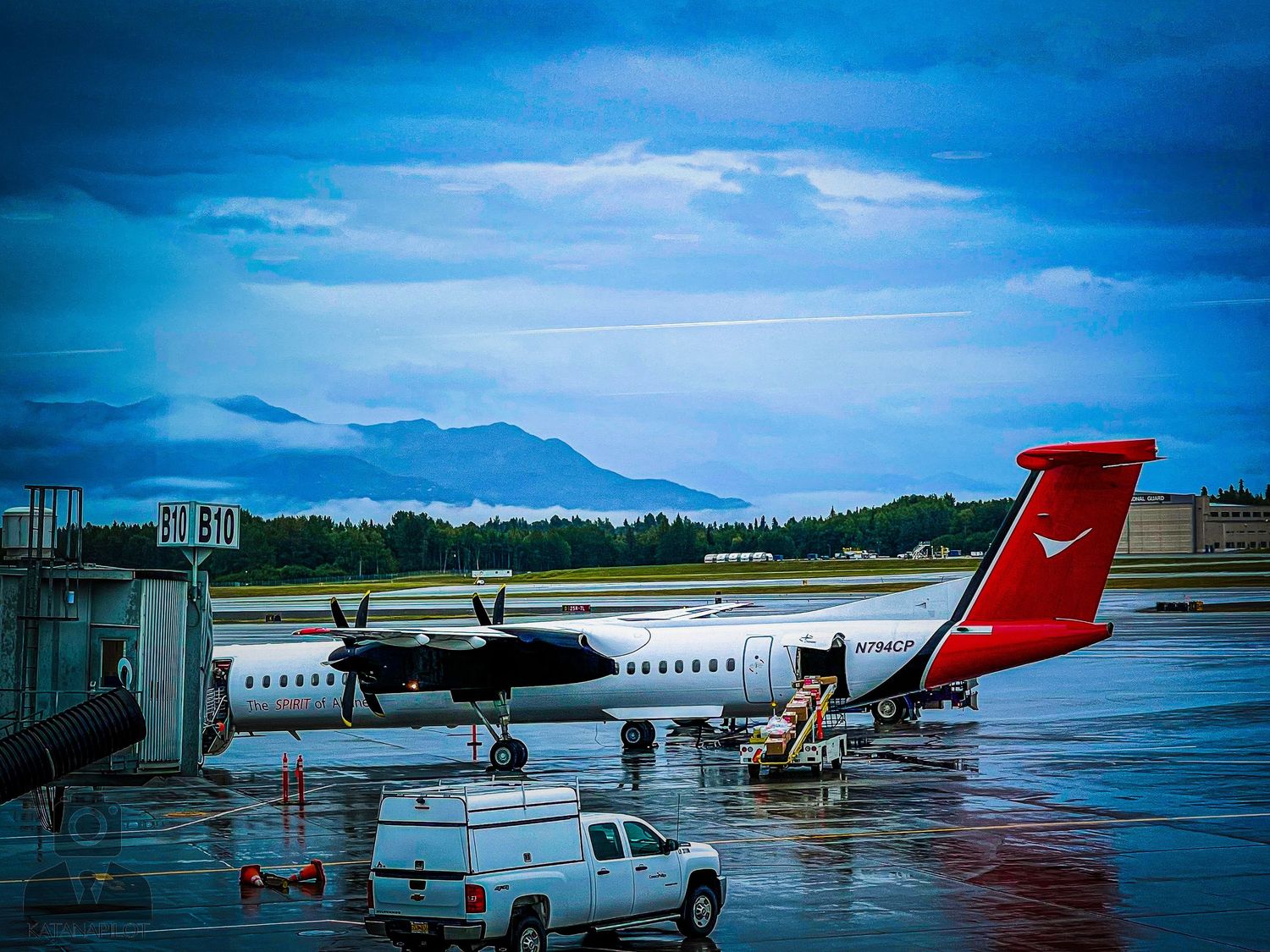 Commercial aircraft on tarmac with mountains visible in background.