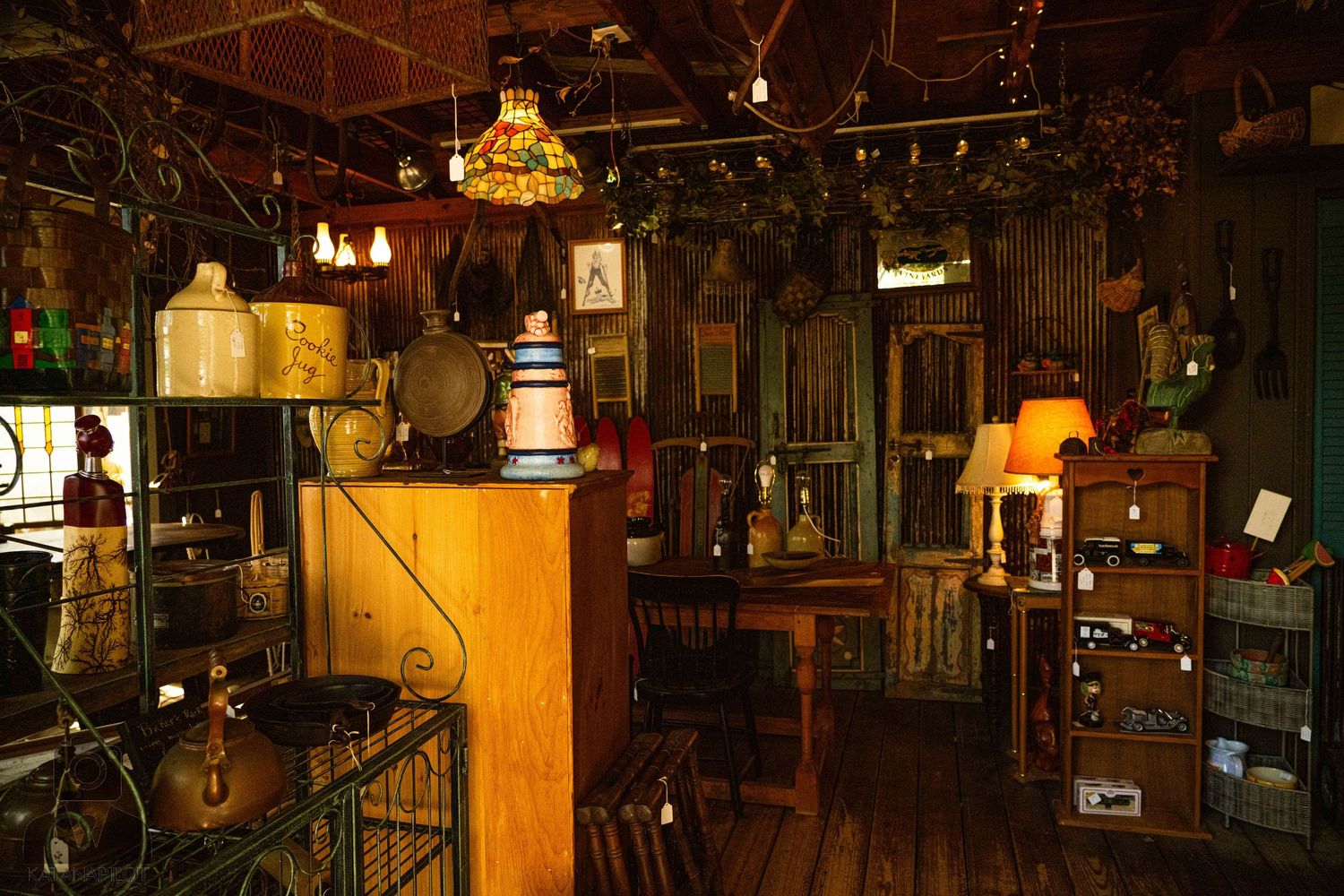Dimly lit antique shop interior with vintage furniture and collectibles under warm lighting.