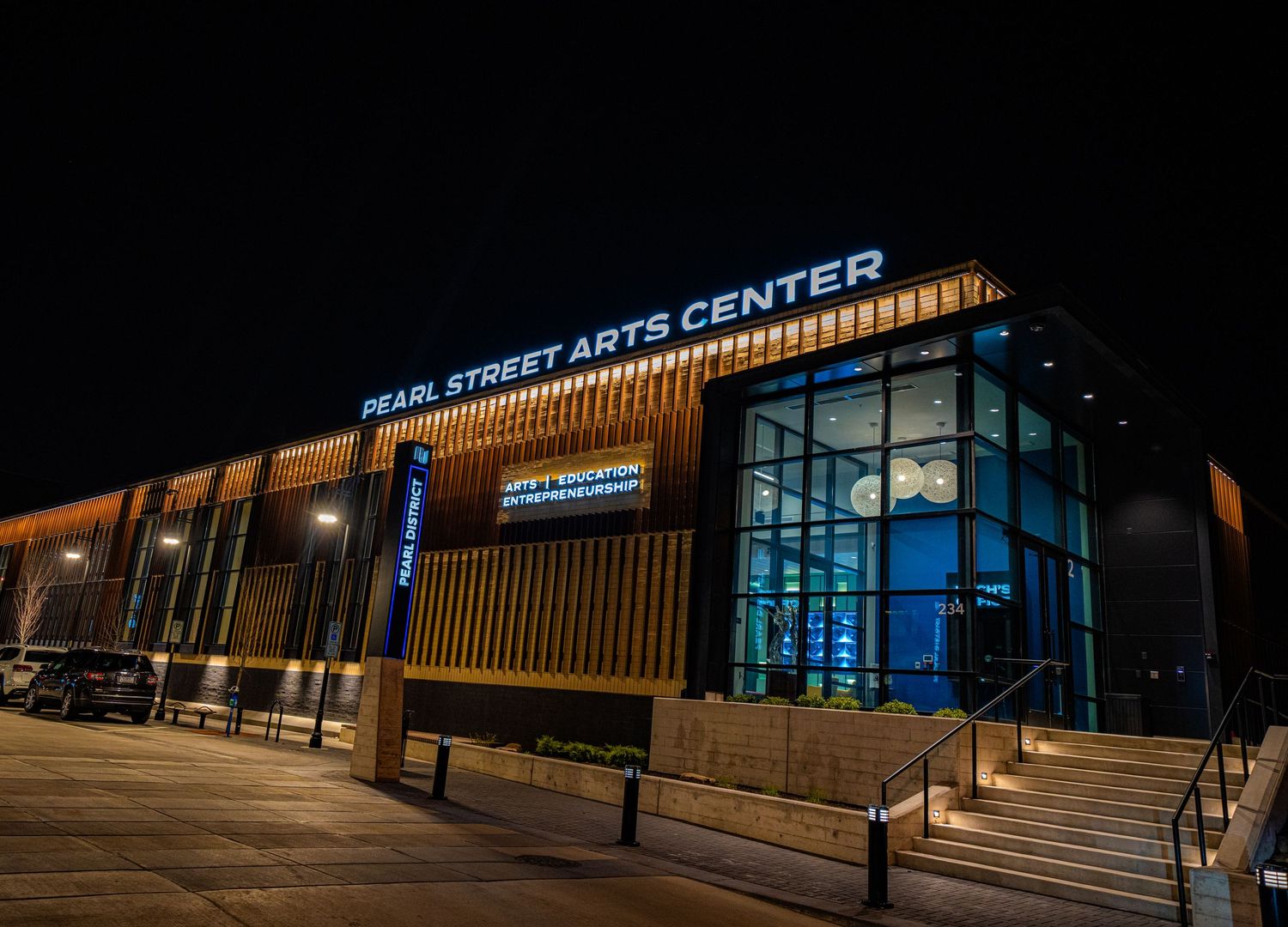 Modern performing arts center exterior lit up at night with illuminated signage.