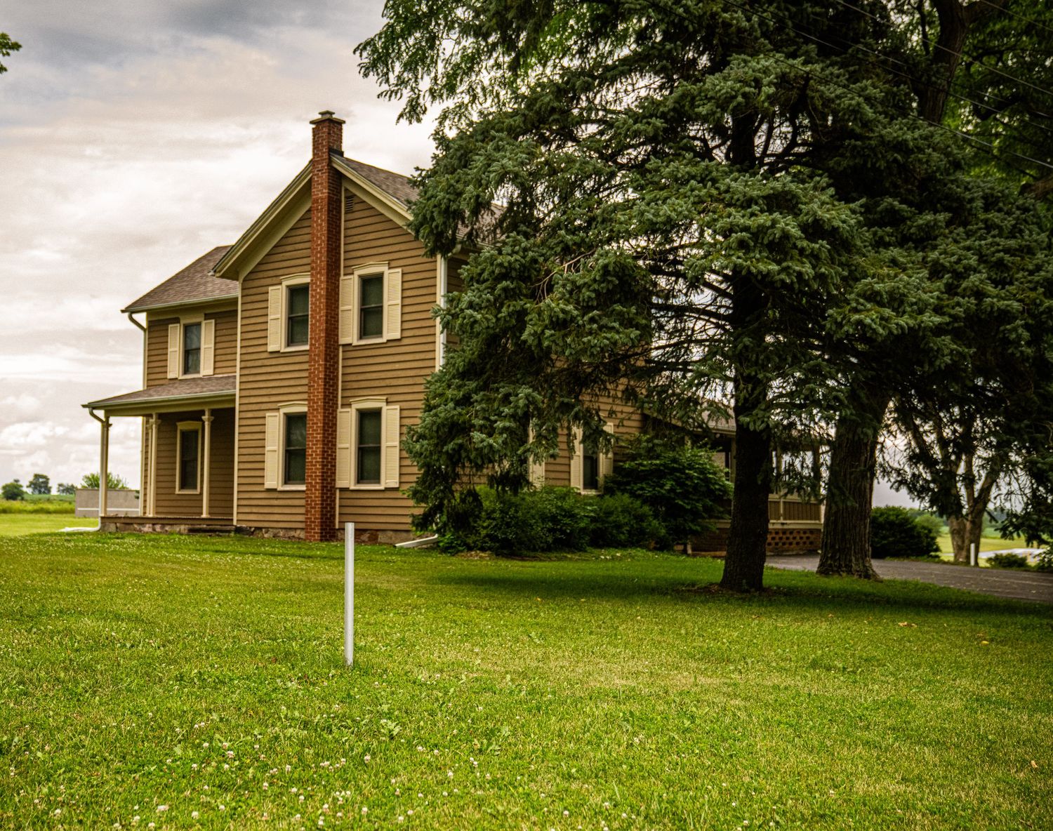 Residential houses set on rolling green hills with mature trees and landscaping.