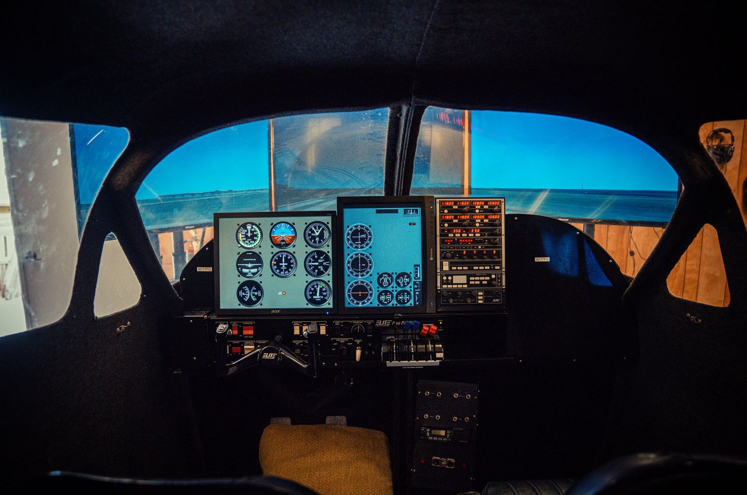 Panoramic view of flight simulator displays showing cockpit instruments against a dark background.