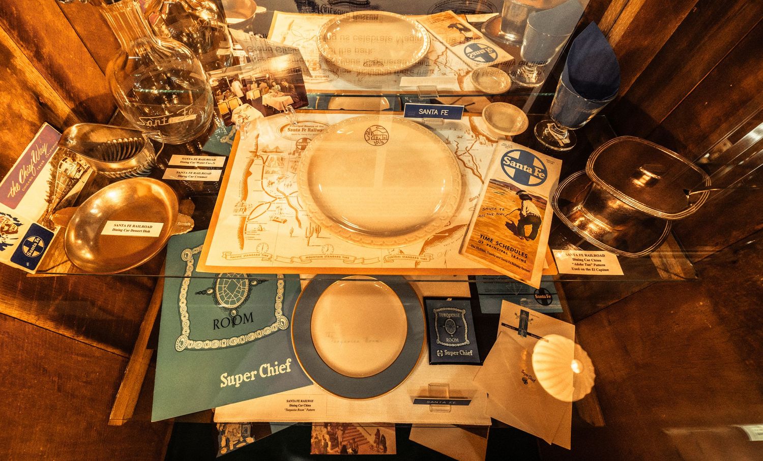 Railroad museum exhibit showing historical dining car plates and service items in wooden cases.