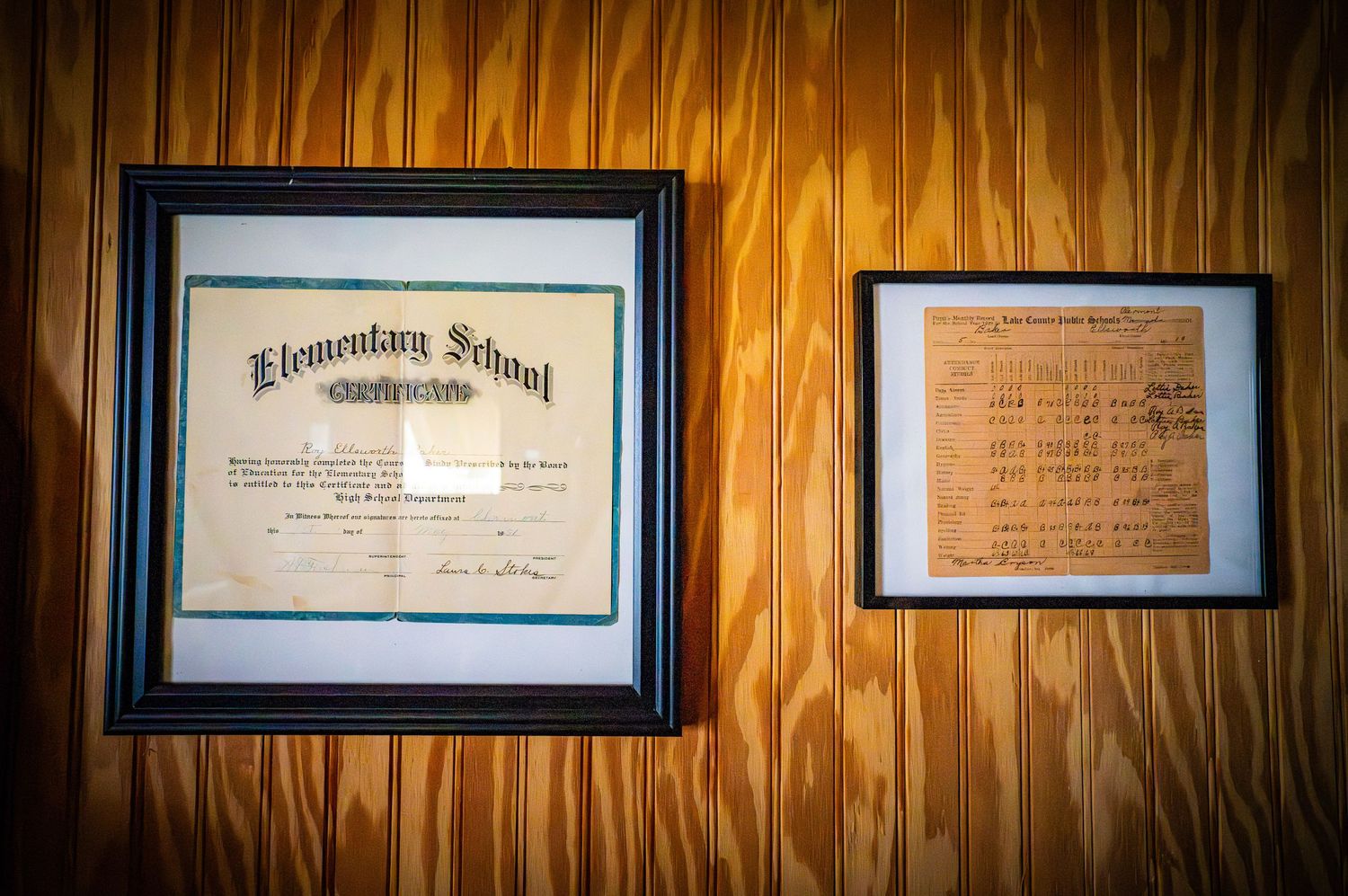 Row of framed historical documents displayed on wood-paneled wall.