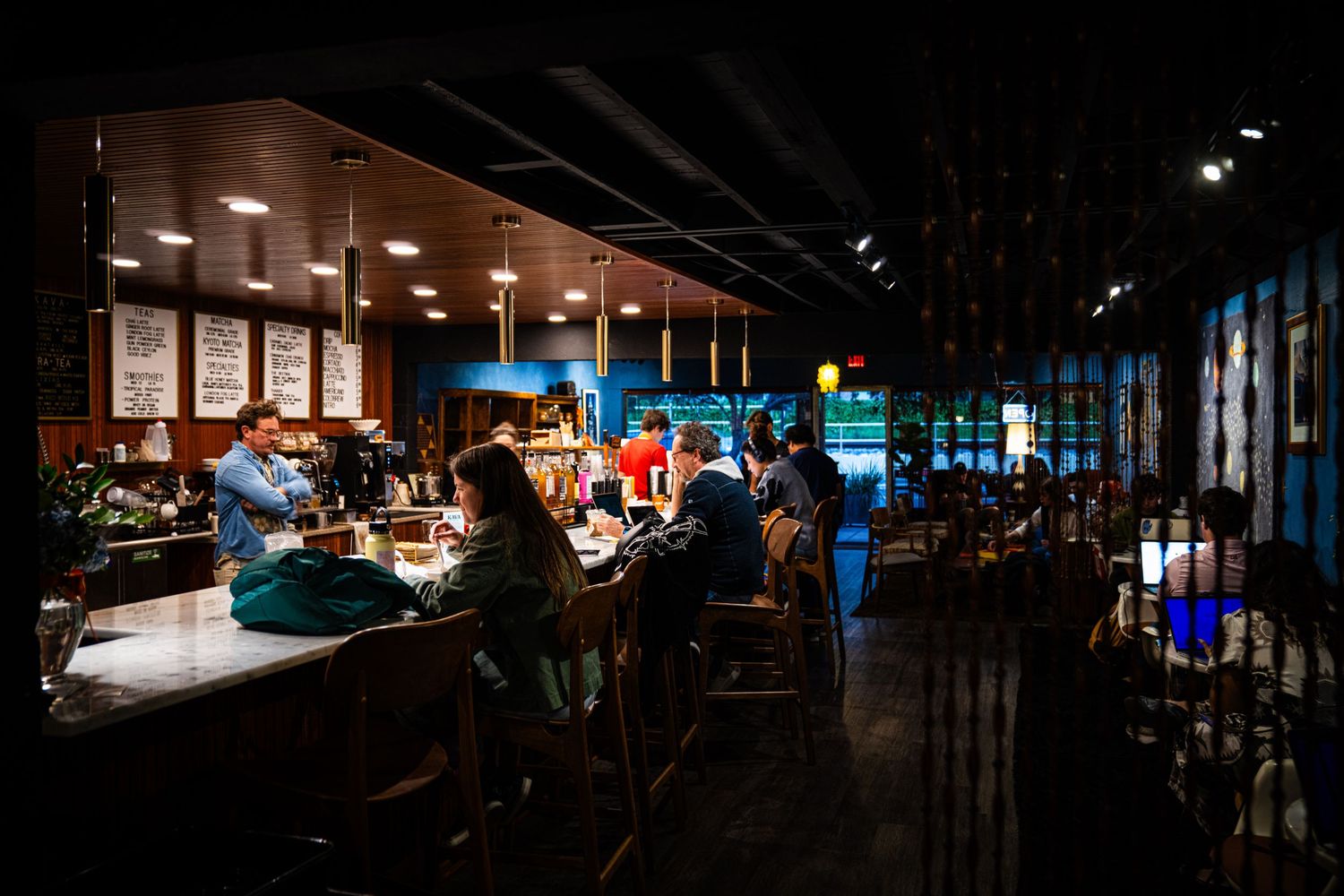 A dark restaurant interior with hanging pendant lights creating a warm ambiance in the evening hours.
