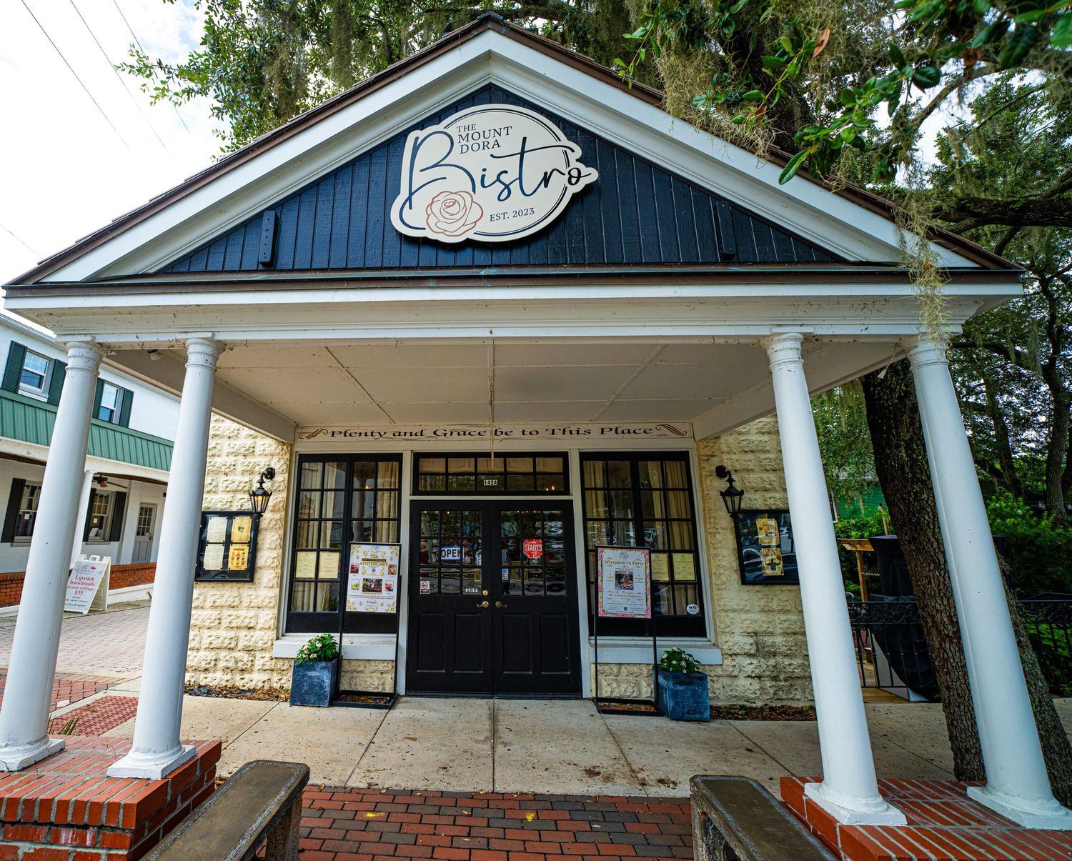 White colonial-style storefront with columns and brick foundation displaying Bistro signage.