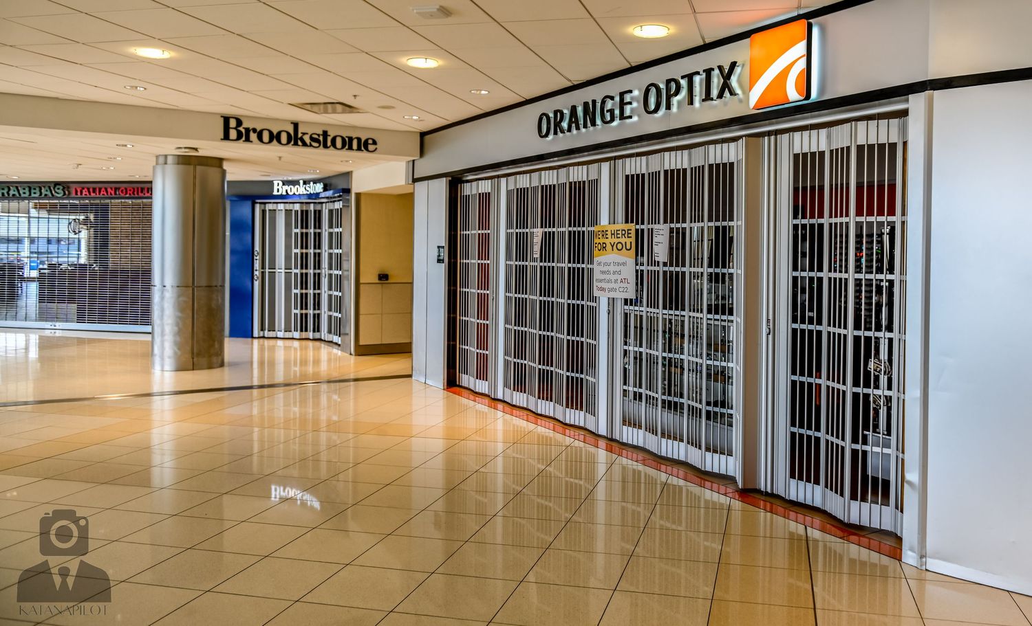 Empty mall hallway with Brookstone signage and Orange Sports store visible in the distance.