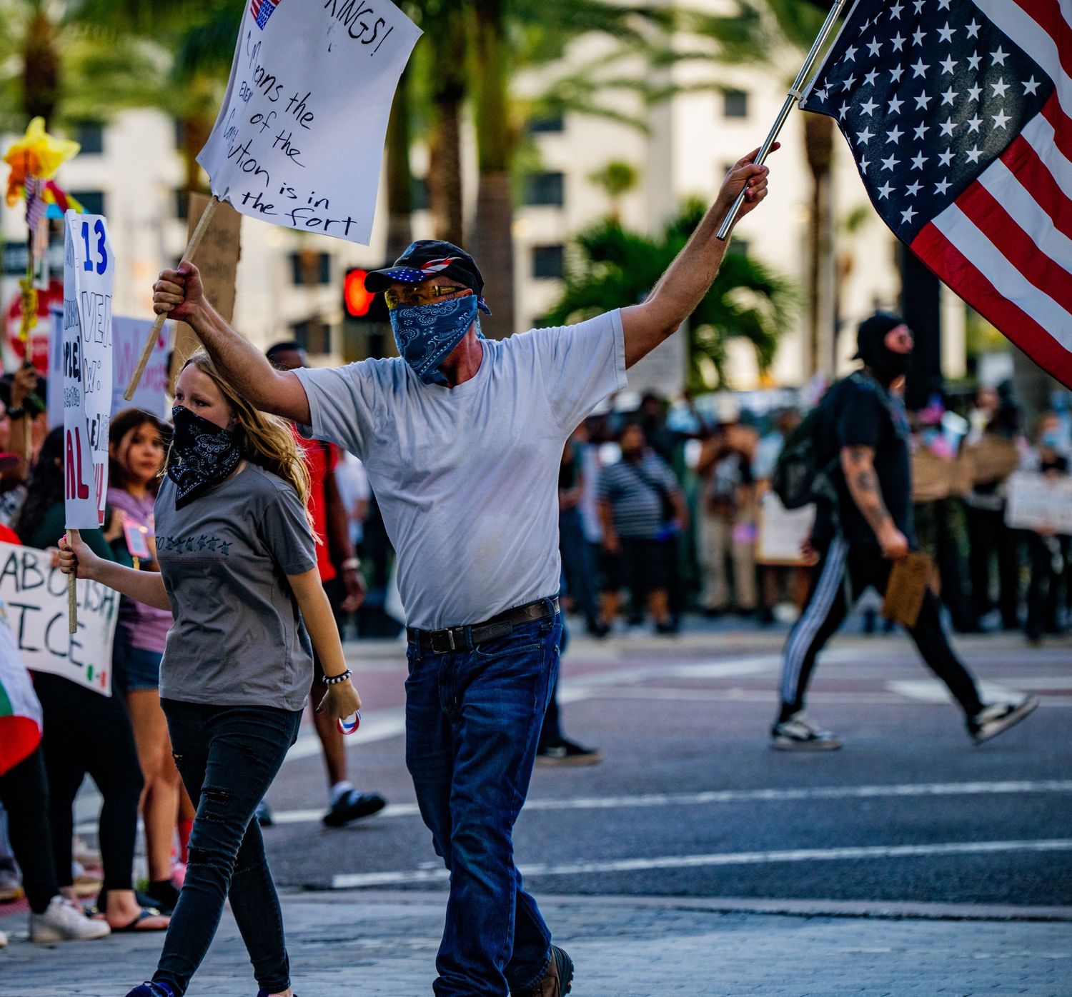 Protester waves American flag while marching in street demonstration.