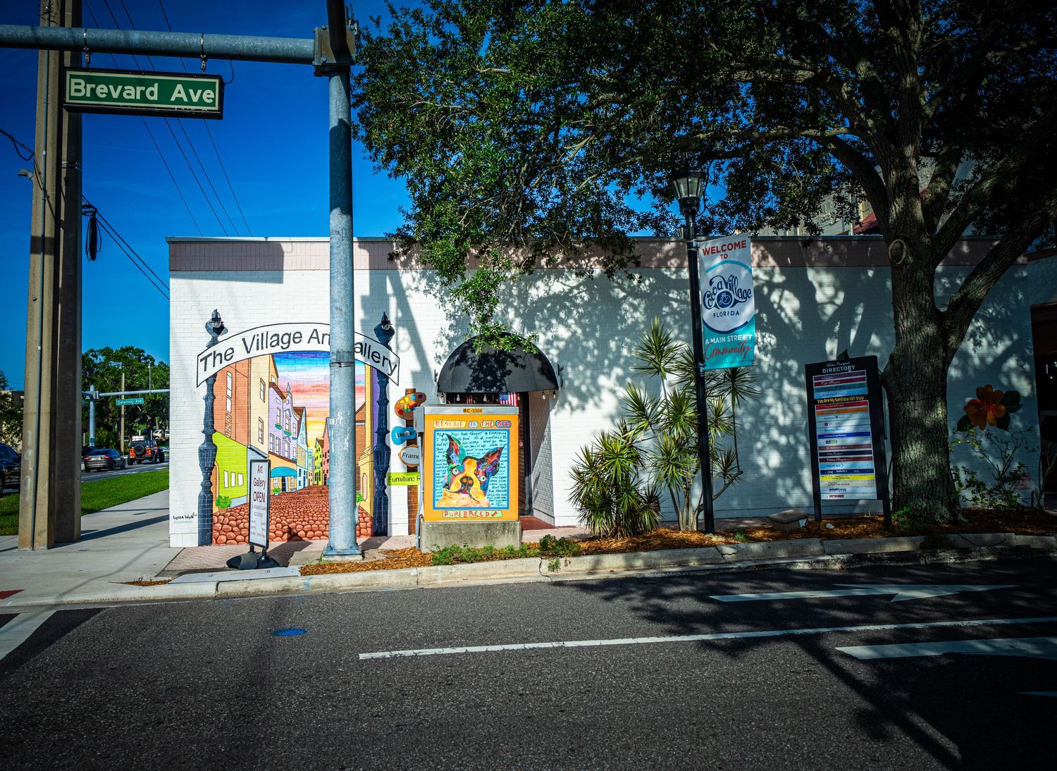 Street view of small town commercial buildings with sidewalks and trees on a sunny day.