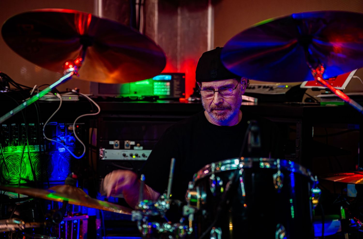 Live music performance with colorful stage lighting and musical equipment visible in the background.