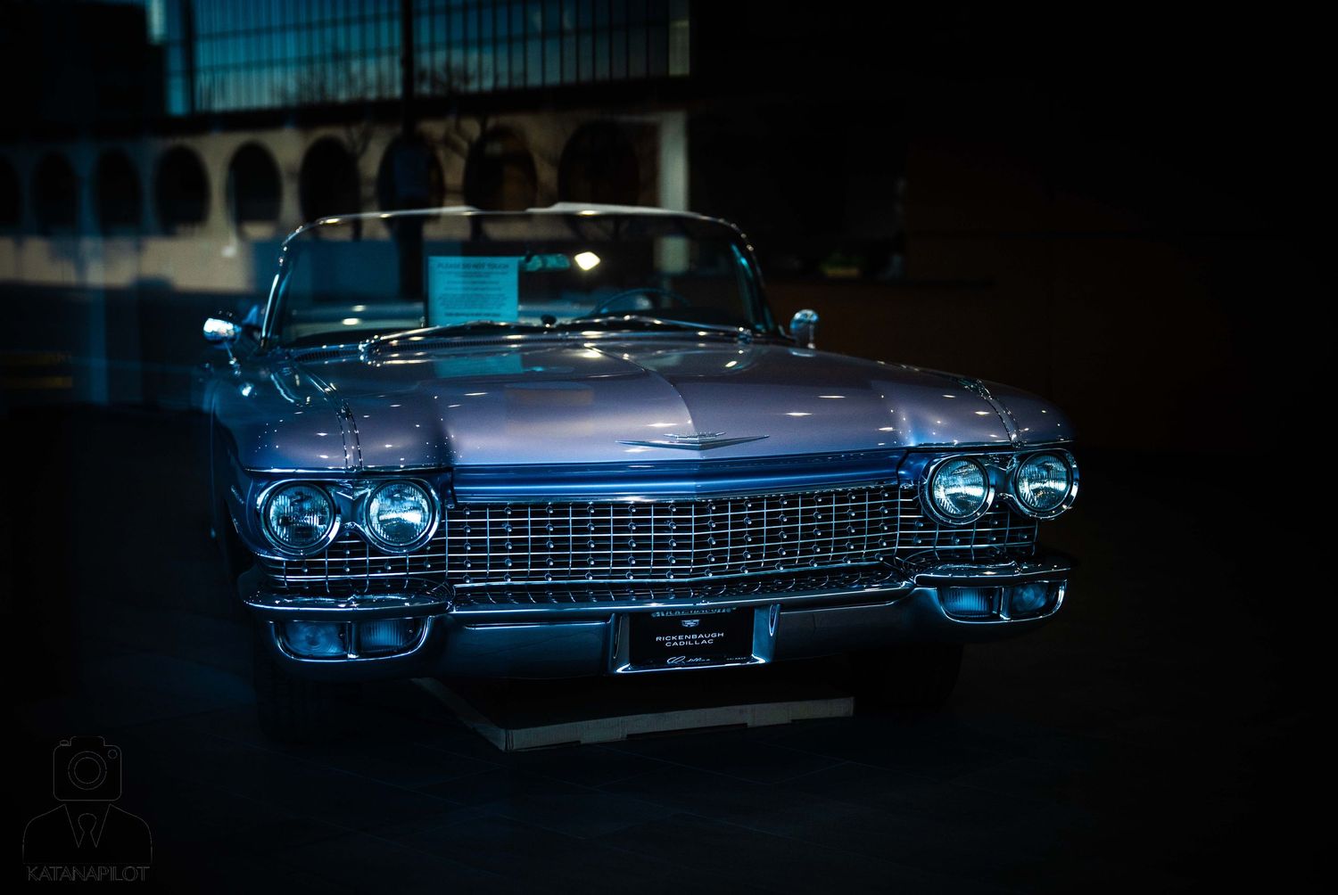 Classic blue vintage Cadillac car photographed at night with dramatic lighting and reflective surfaces.