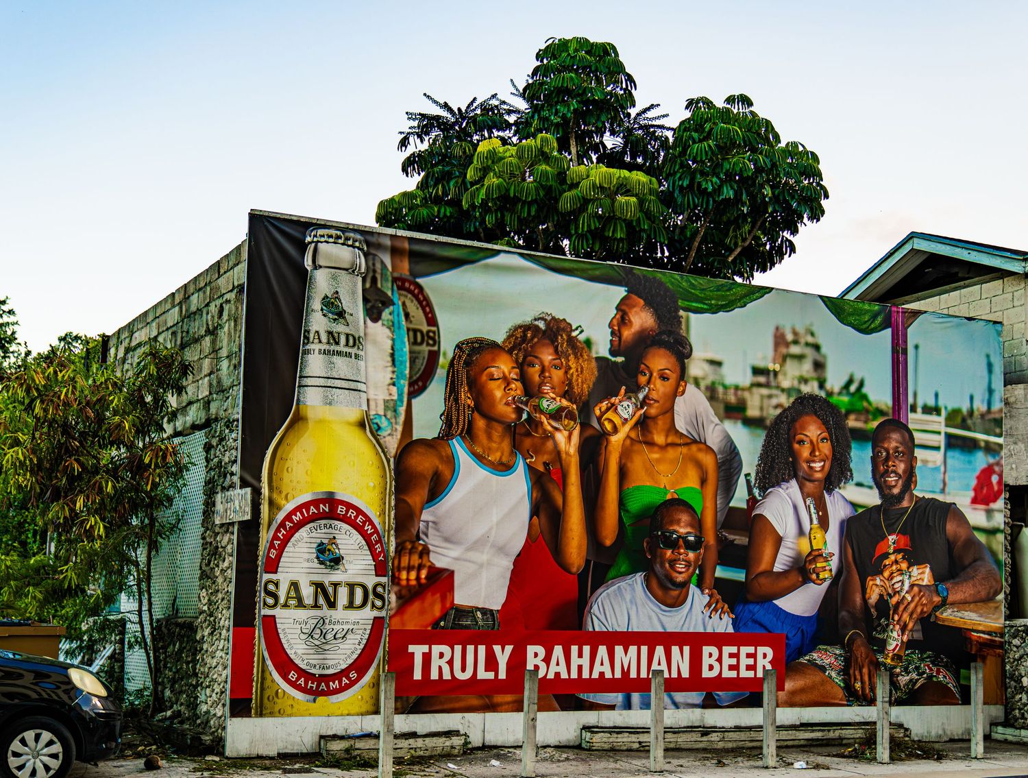 Sands Truly Bahamian Beer billboard advertisement featuring locals celebrating in Nassau, Bahamas.