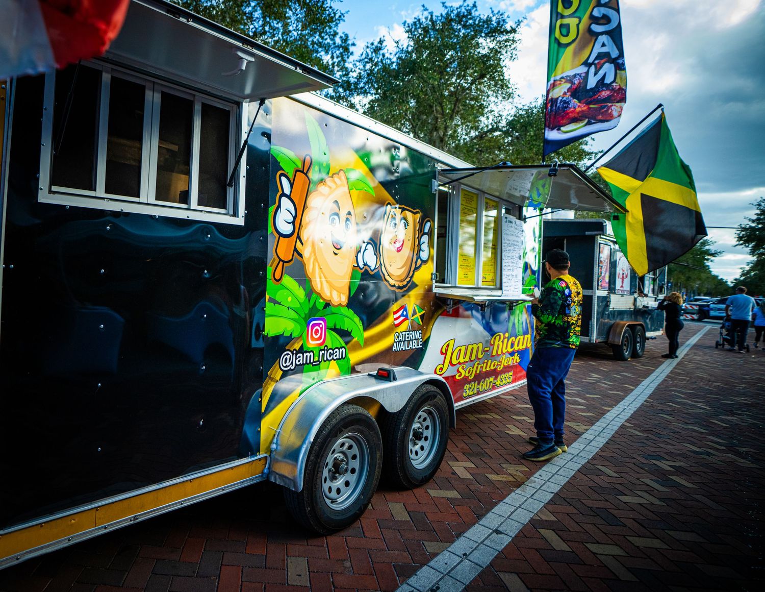 A yellow food truck with a ramp extended parked on a street during daytime.