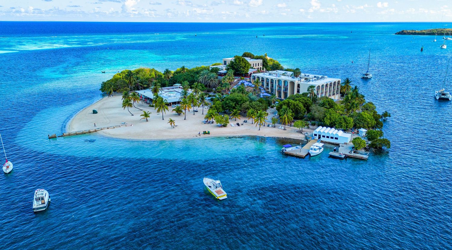 Aerial view of luxury resort on private tropical island surrounded by turquoise waters.