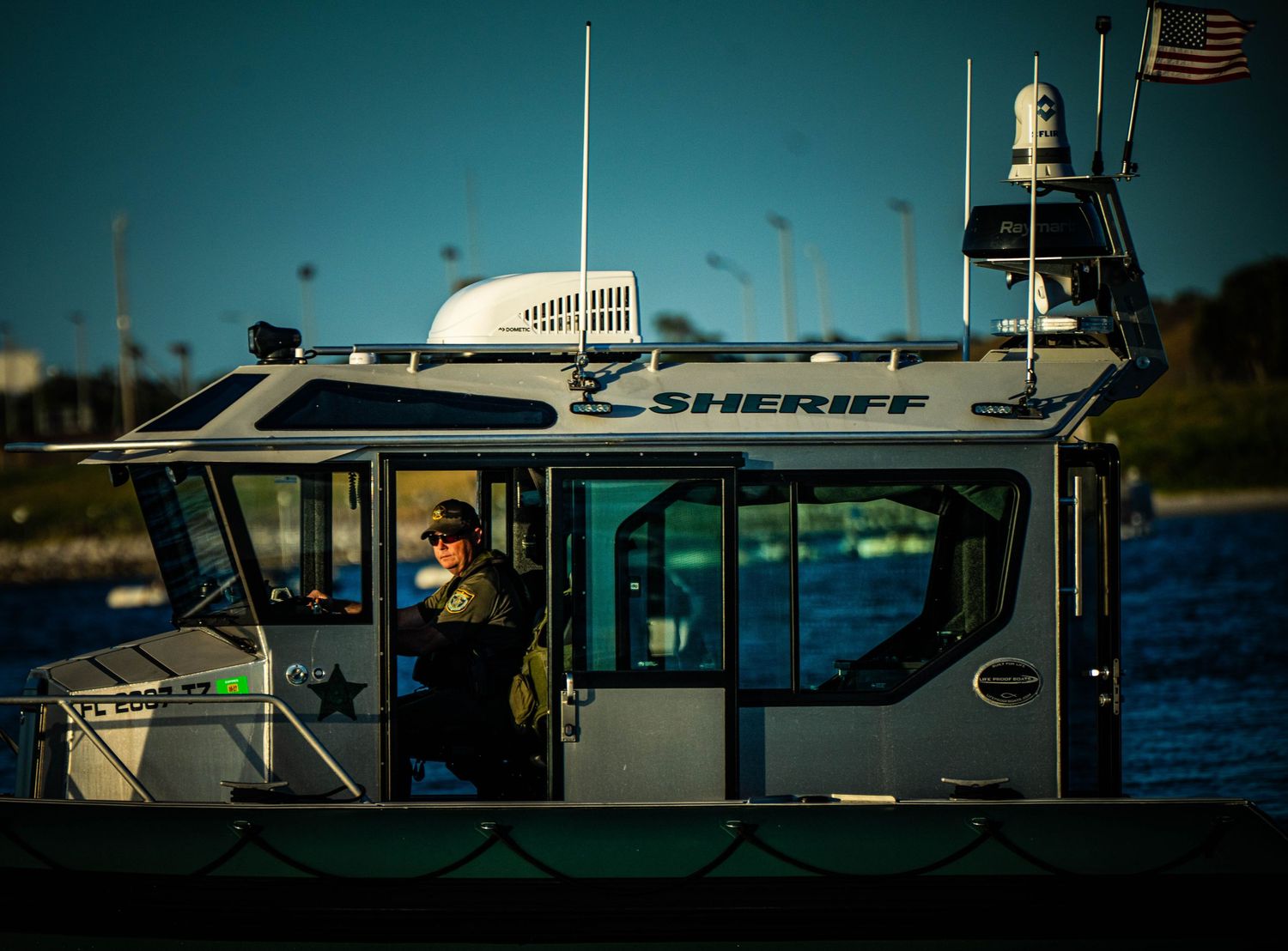 Silhouettes of boat cabins and equipment against a blue sky during sunset on the water.