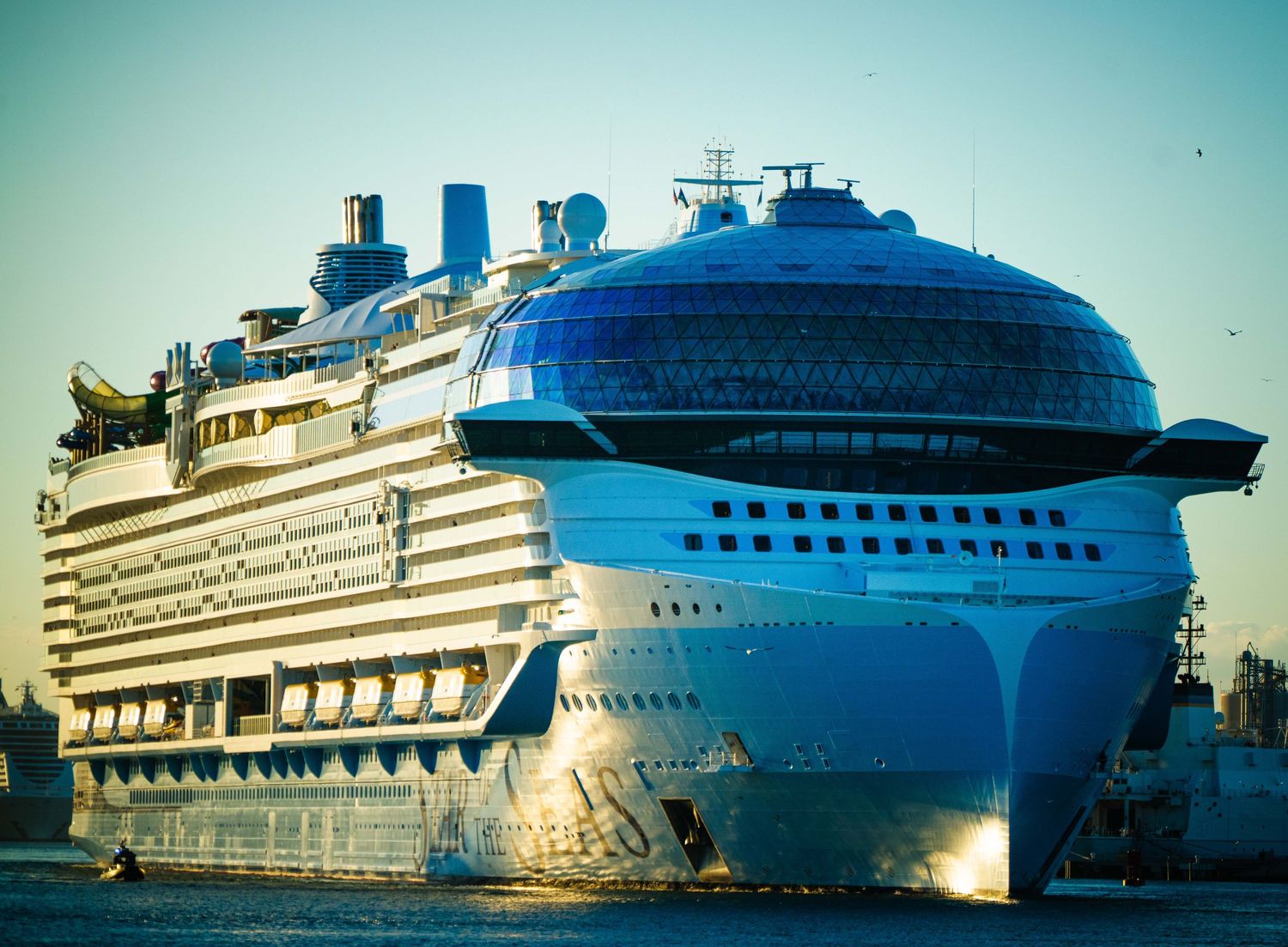 Luxury cruise ships docked at a port during sunset with golden sunlight reflecting off their white exteriors.
