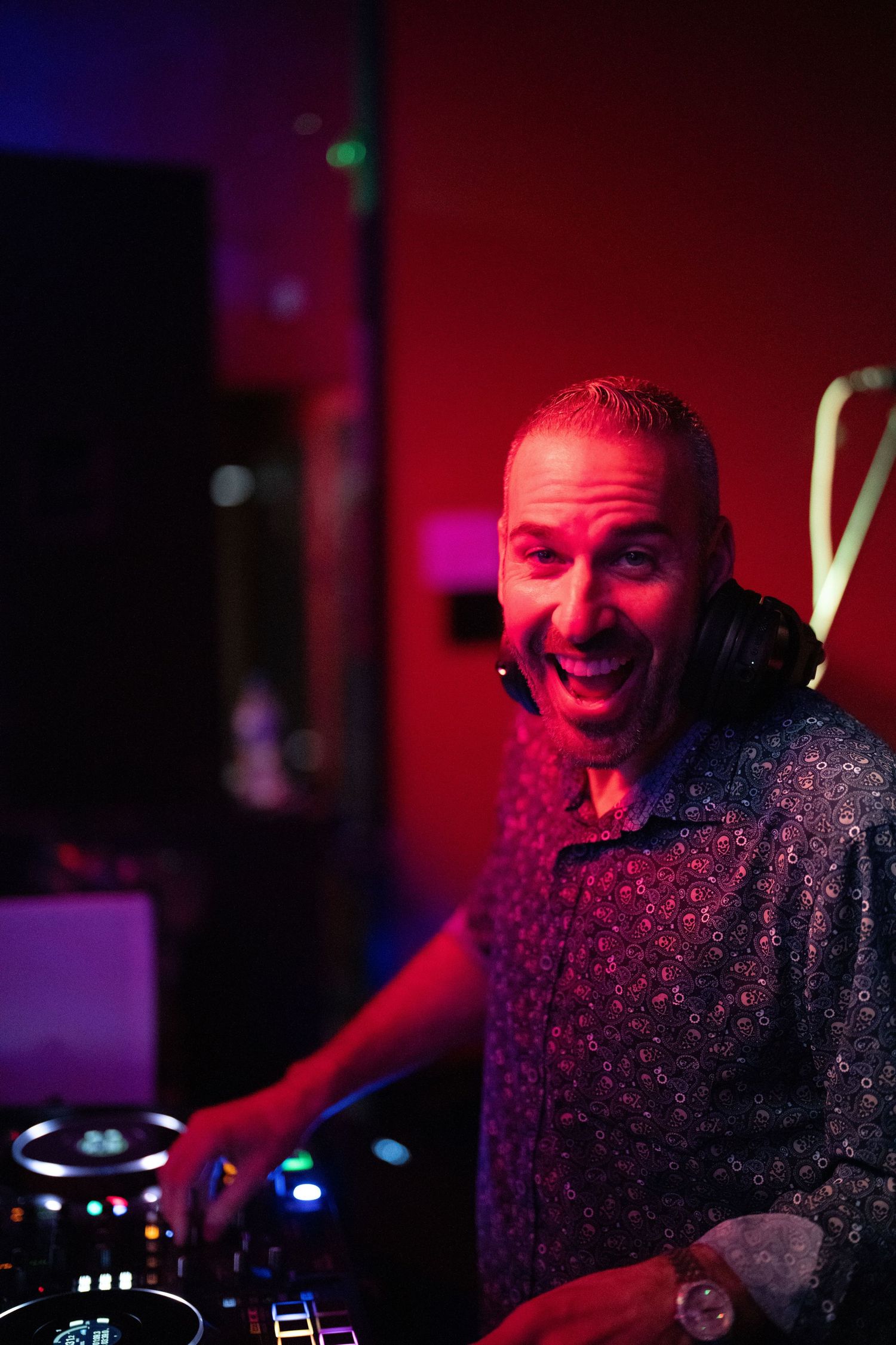 DJ performs at mixing console under dramatic red stage lighting.
