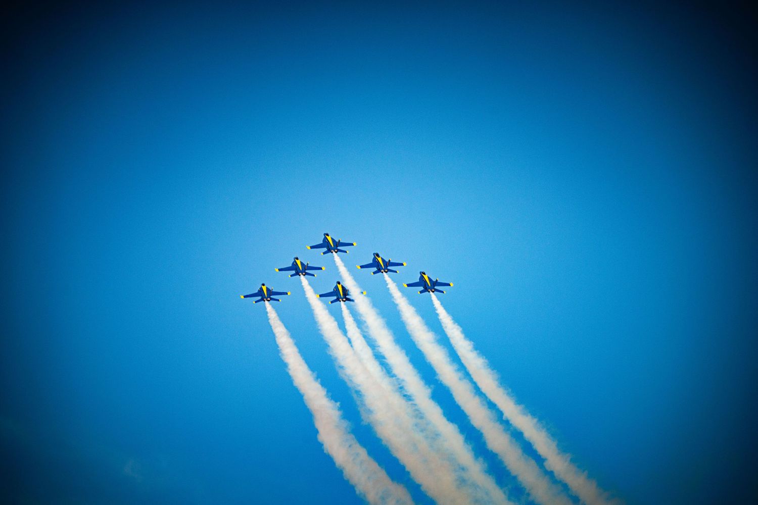 Formation of military jets creating parallel smoke trails during an airshow performance.