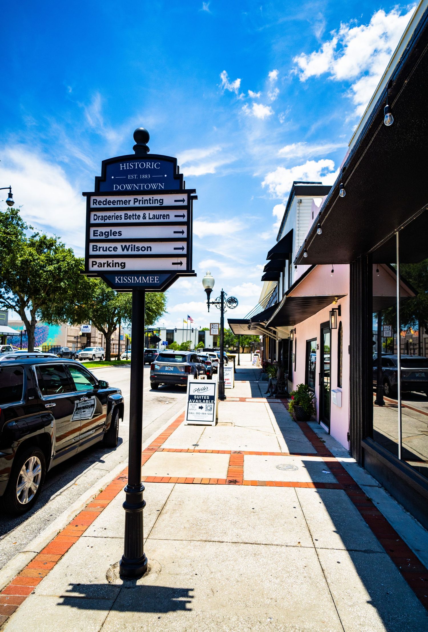 Historic downtown wayfinding signs and lampposts along brick-lined sidewalk.