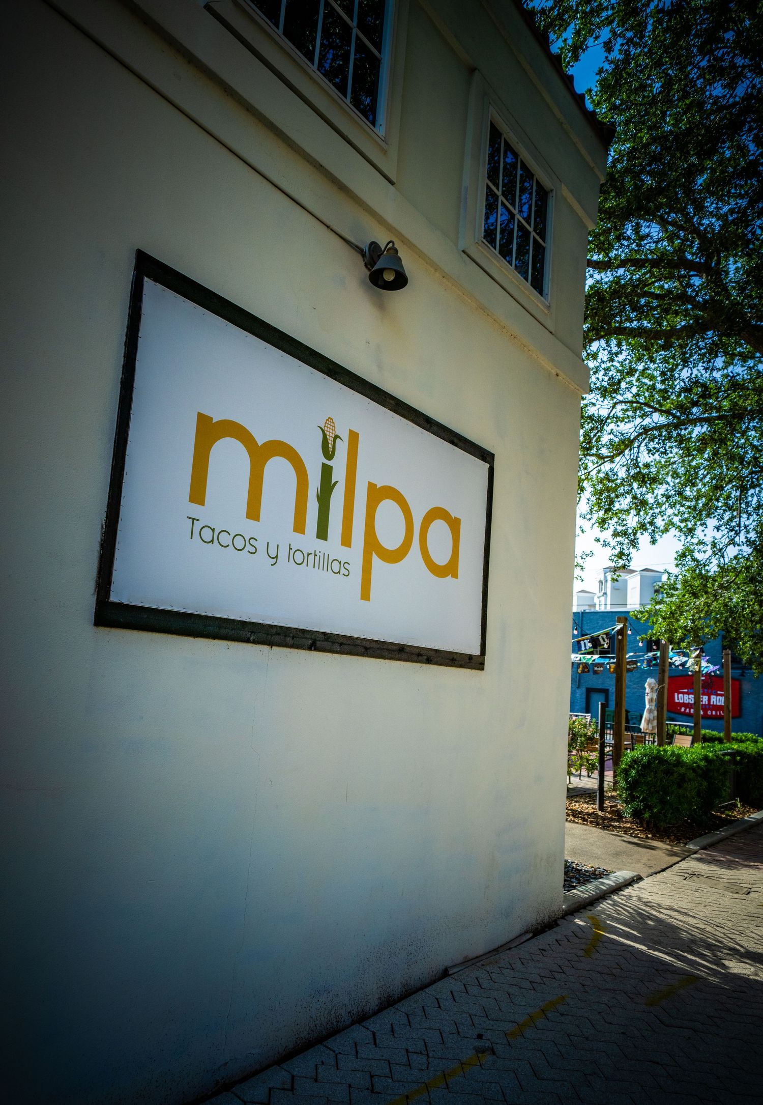 White building wall with minimalist 'mpa' restaurant signage in gold lettering.