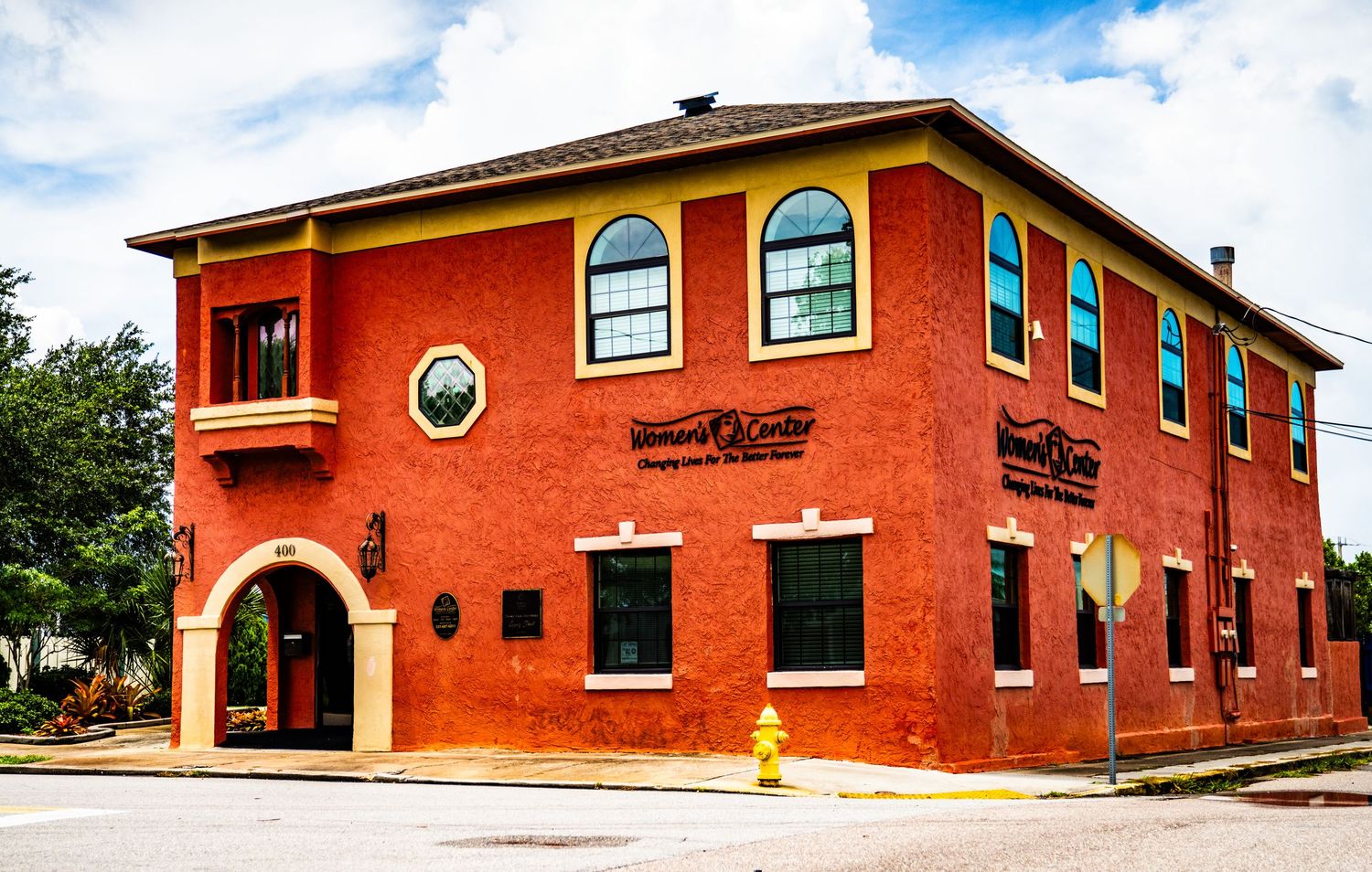 Panoramic view of a terracotta-colored commercial building with arched windows and Spanish-style architecture.