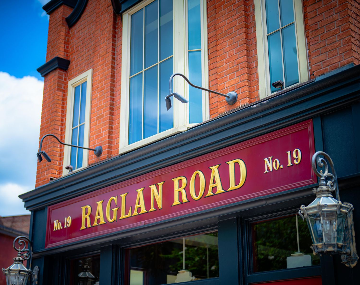 Raglan Road Irish pub sign at No. 19, featuring gold lettering on a red background with a classic brick facade.