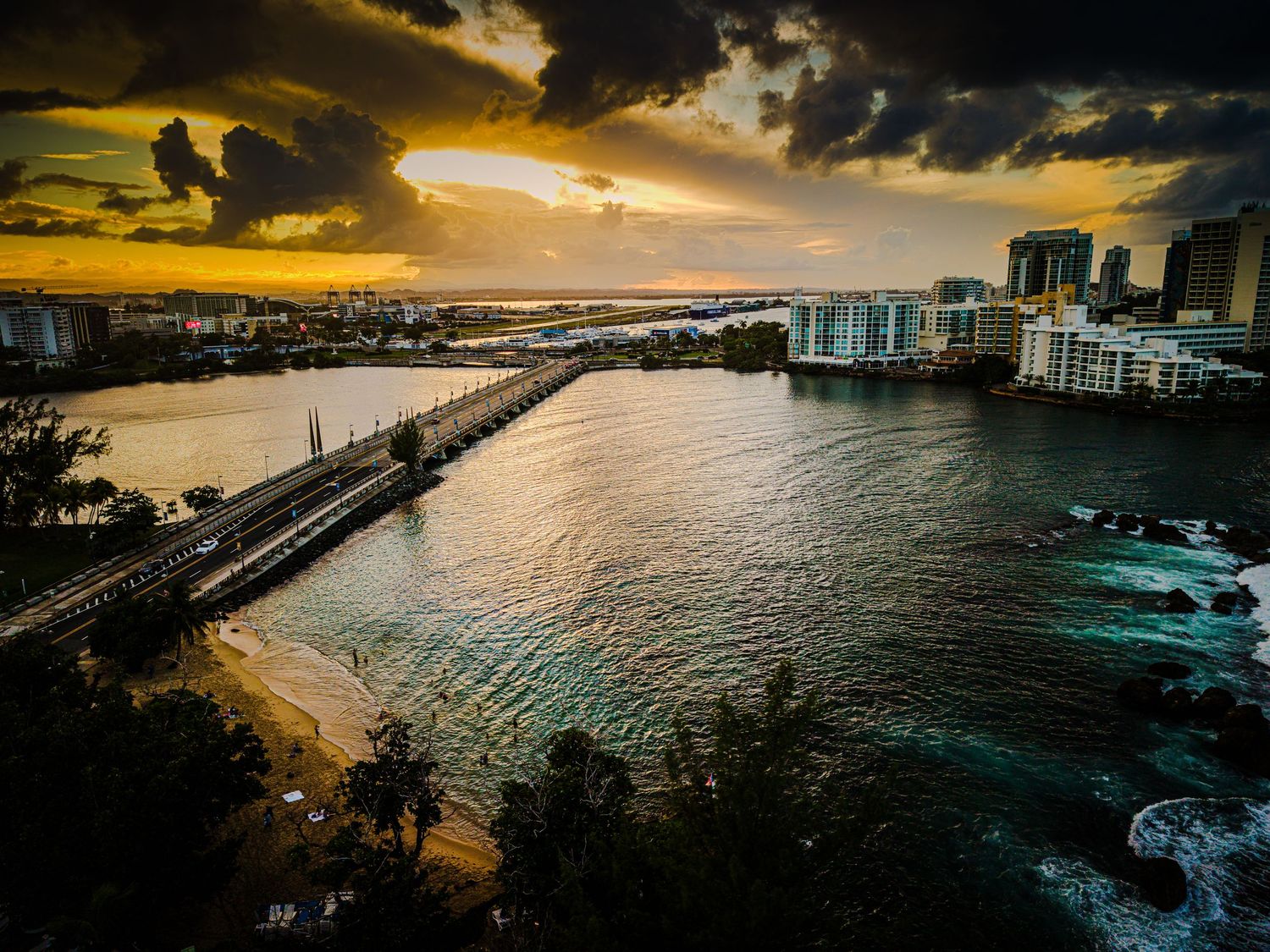 Panoramic aerial view of Miami Beach coastline and buildings during dramatic golden sunset over ocean waters.