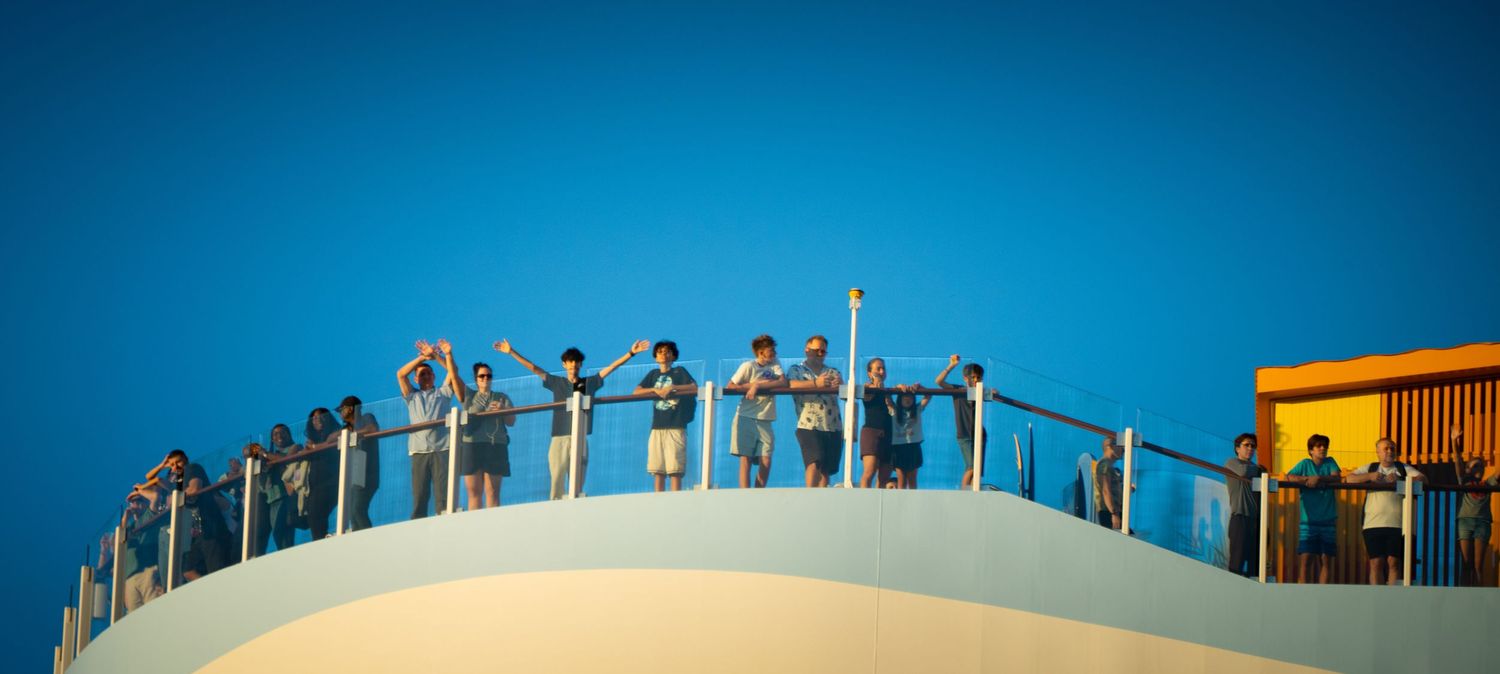 Silhouettes of people standing on a viewing platform against a vibrant blue and orange sunset sky.