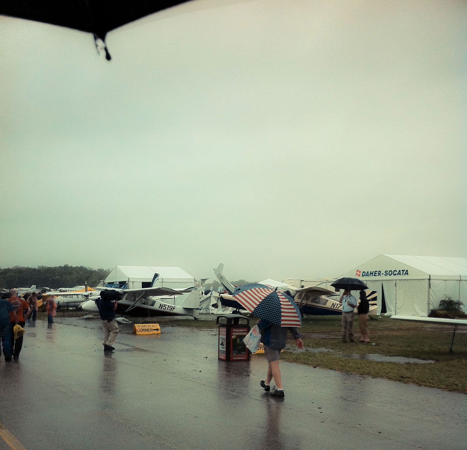 Small aircraft tied down on a foggy airfield during stormy weather conditions.