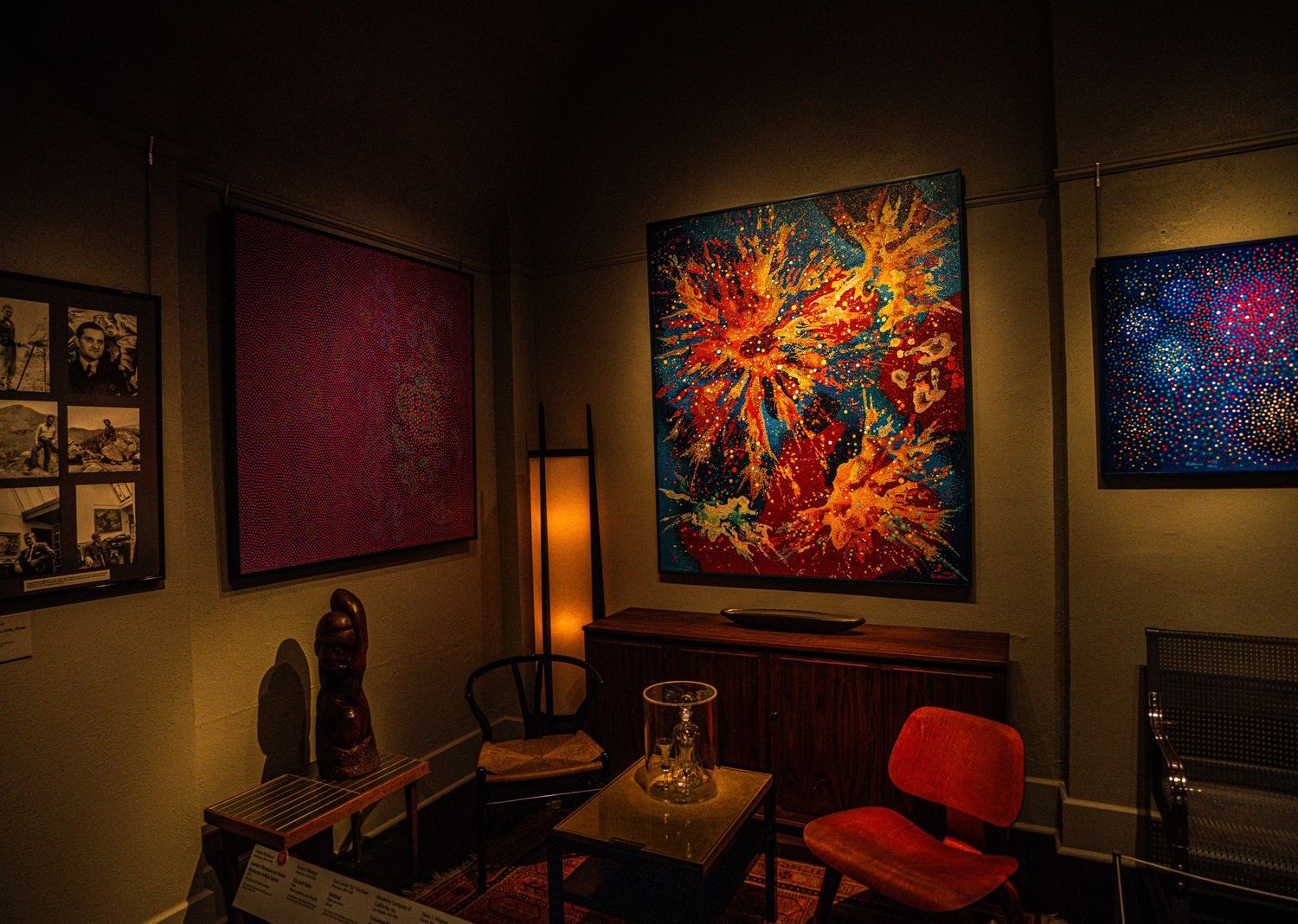 A cozy art gallery corner with vibrant abstract paintings and modern furniture illuminated by warm lighting.