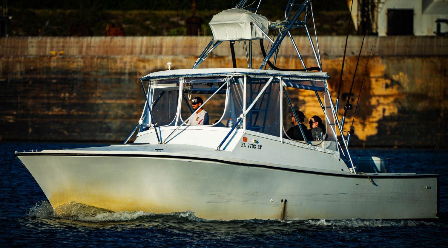 Six white sport fishing boats lined up in a row at a marina dock during daytime.