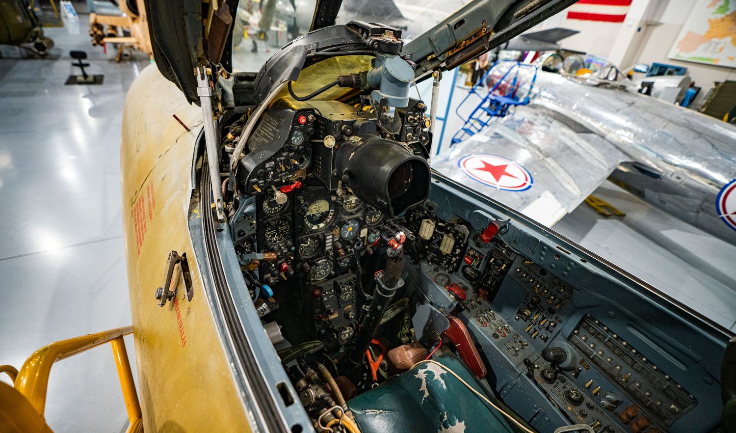 Close-up view of a military fighter jet cockpit with complex instrumentation panels on display in an aviation museum.