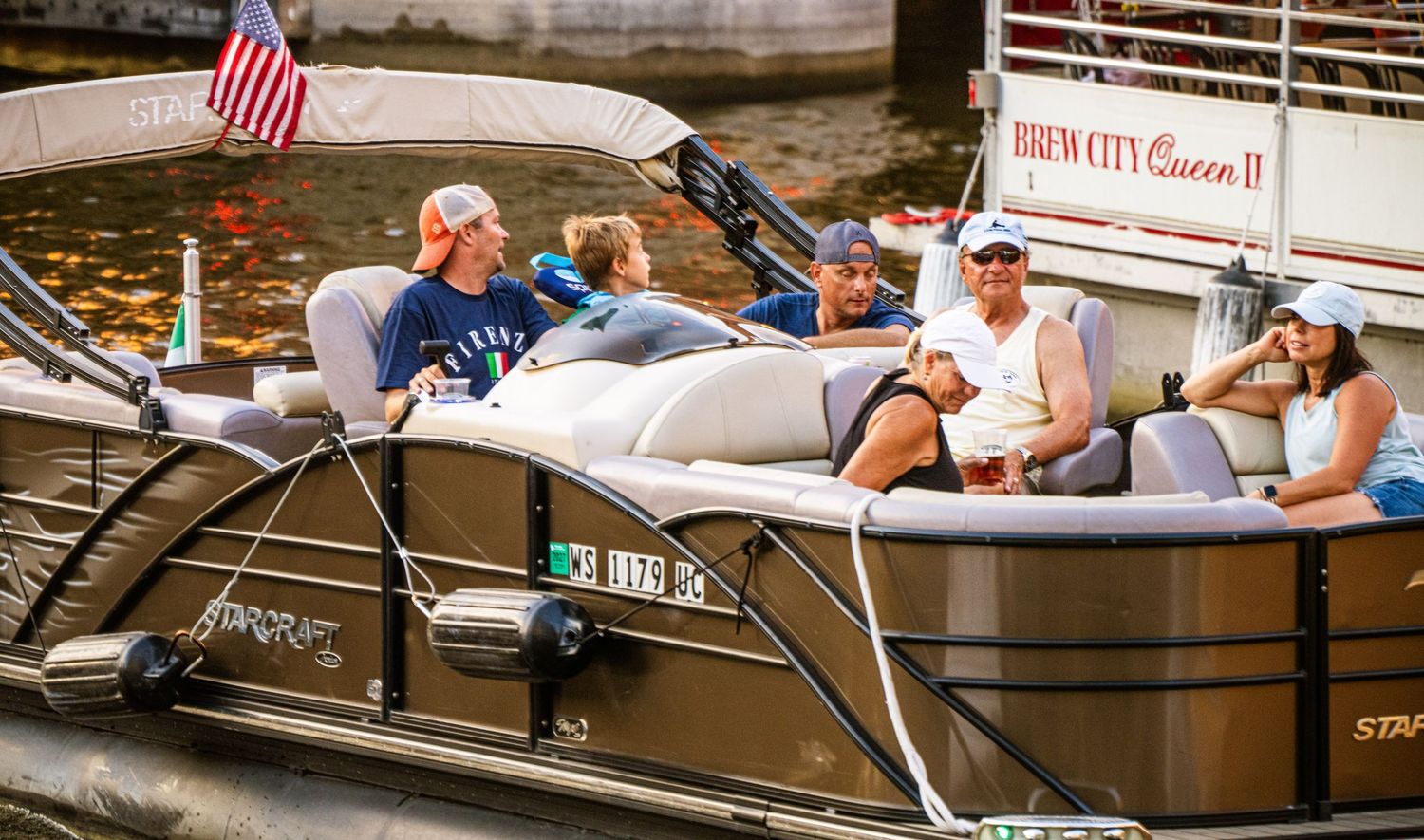 Multiple rental boats docked at an urban waterway with passengers enjoying leisure time.