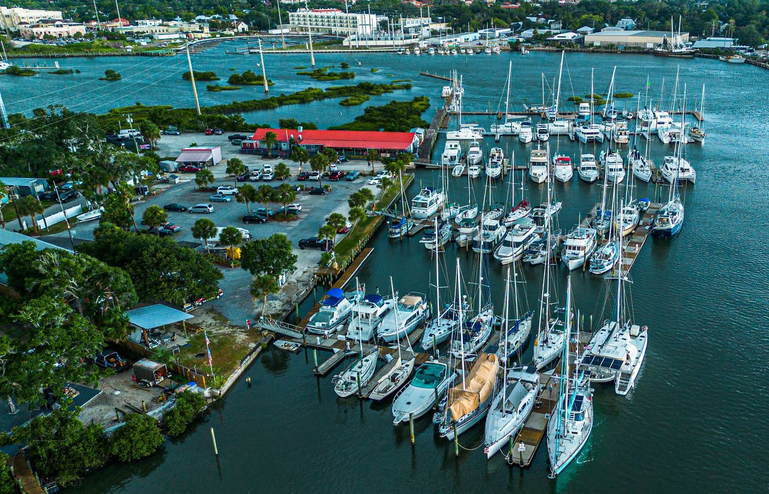 Panoramic view of a waterfront marina filled with sailboats and yachts on a sunny day.