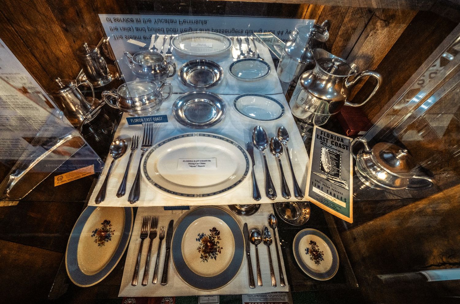 Elegant table settings with fine china plates and crystal glassware in a rustic wooden restaurant interior.
