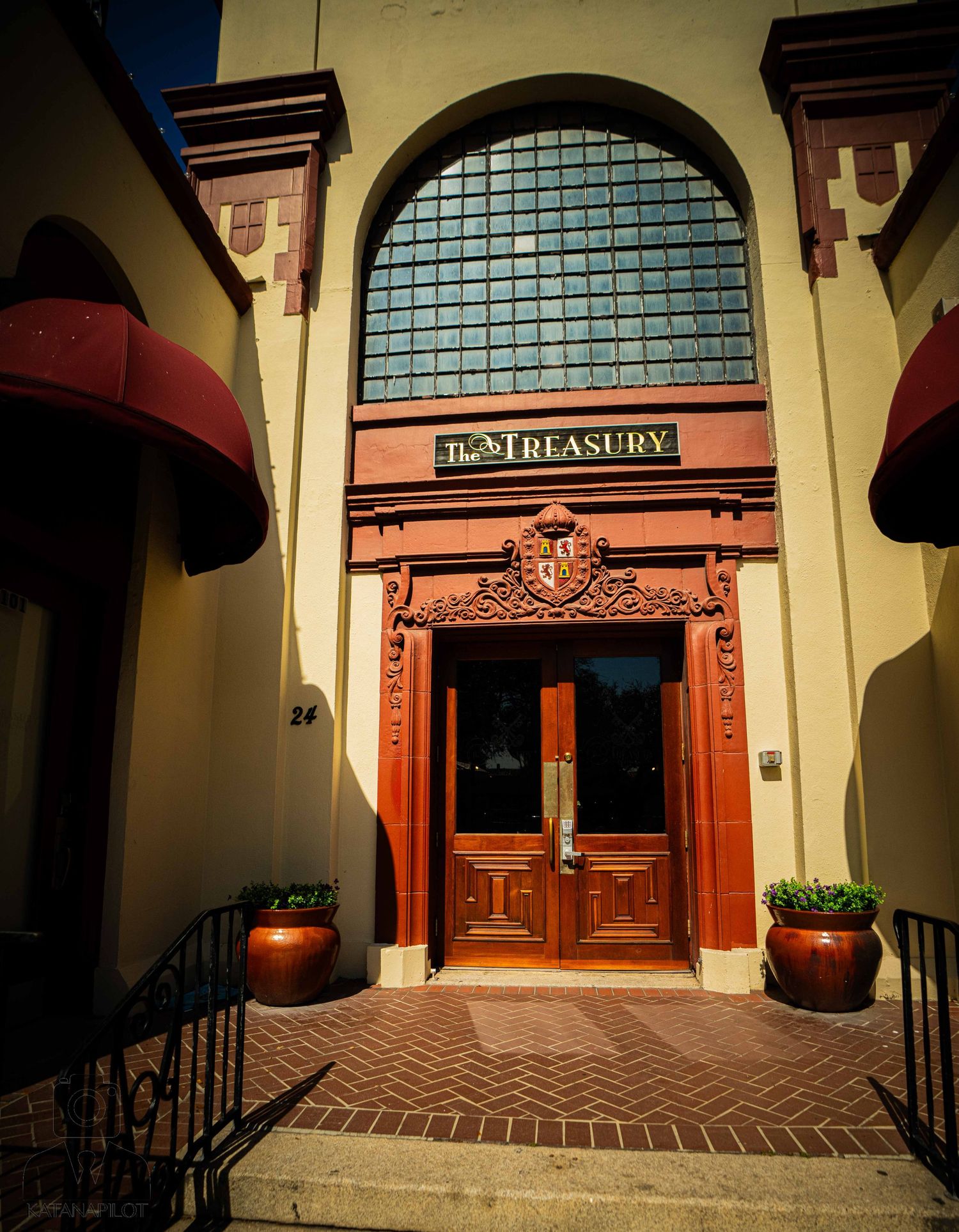 Row of arched entryways with ornate wooden doors and transom windows in Spanish colonial building.
