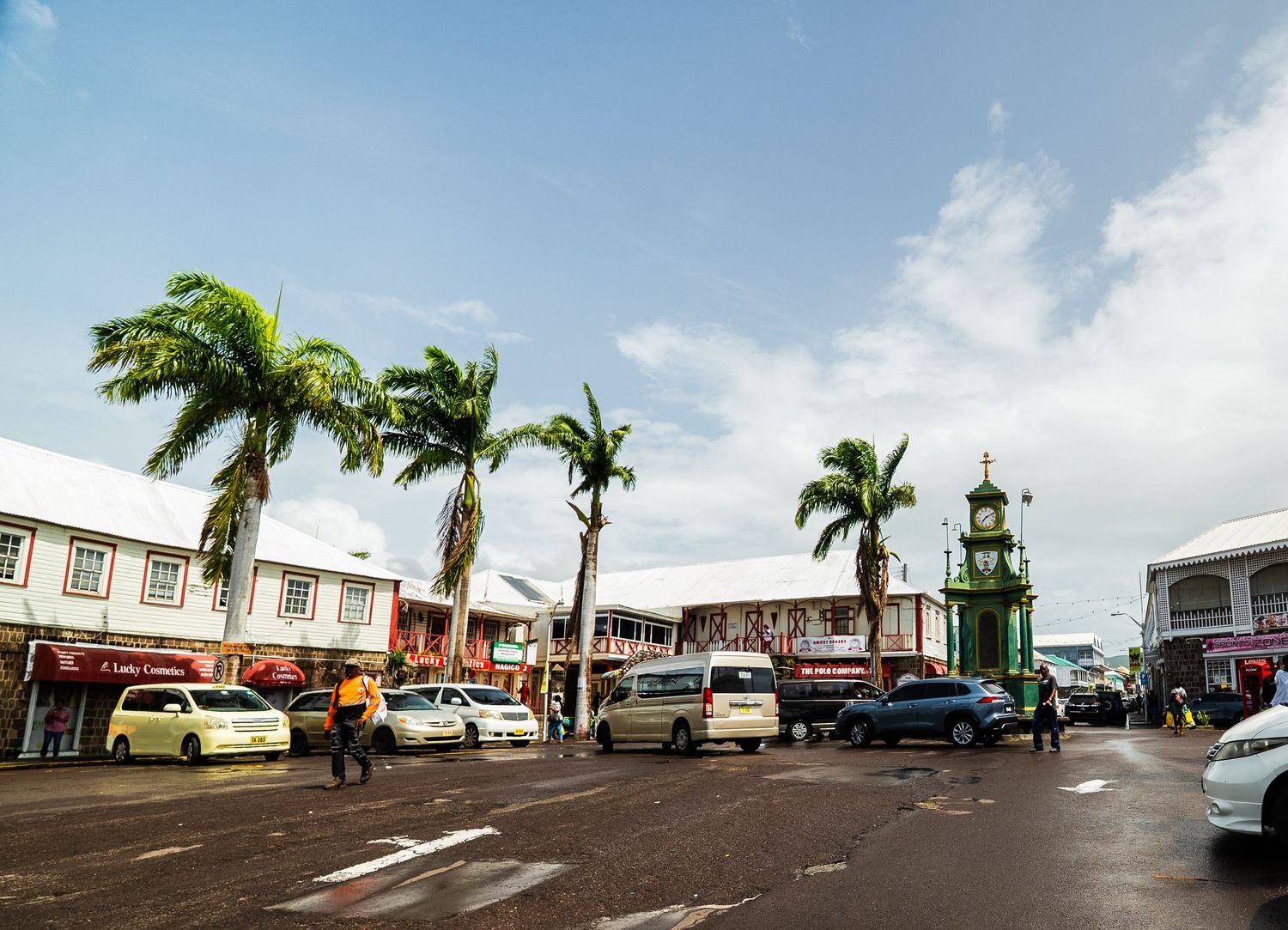 Panoramic view of a commercial district with palm trees and parked vehicles.