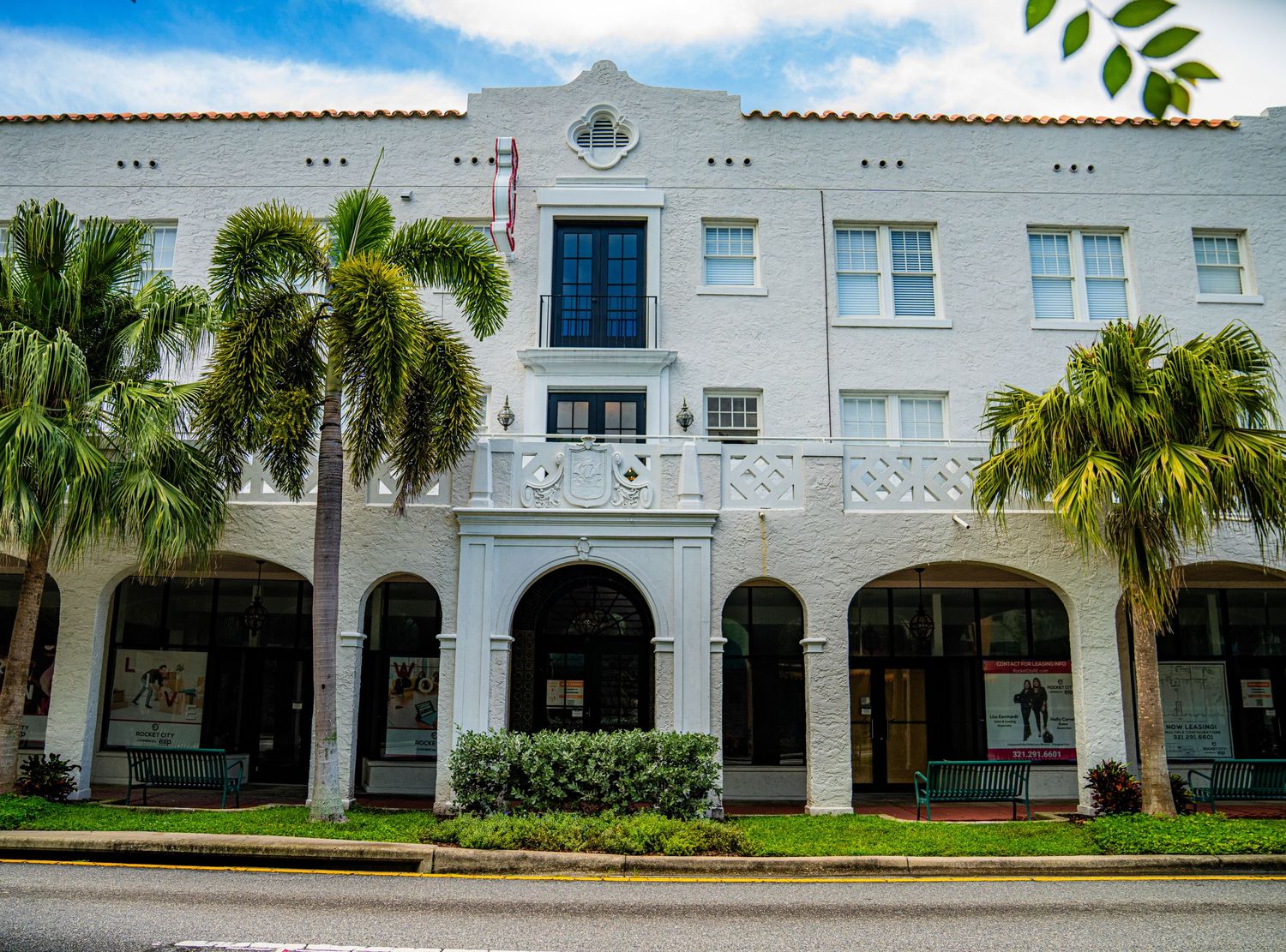White colonial style building with arched walkways and palm trees in Florida.