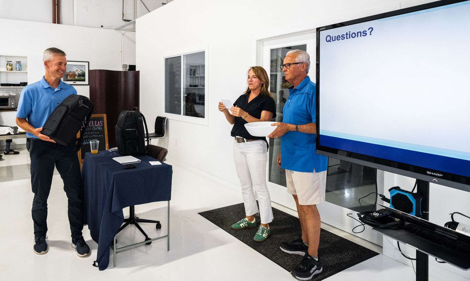 Interactive presentation setup with multiple screens and white chairs in an industrial venue.