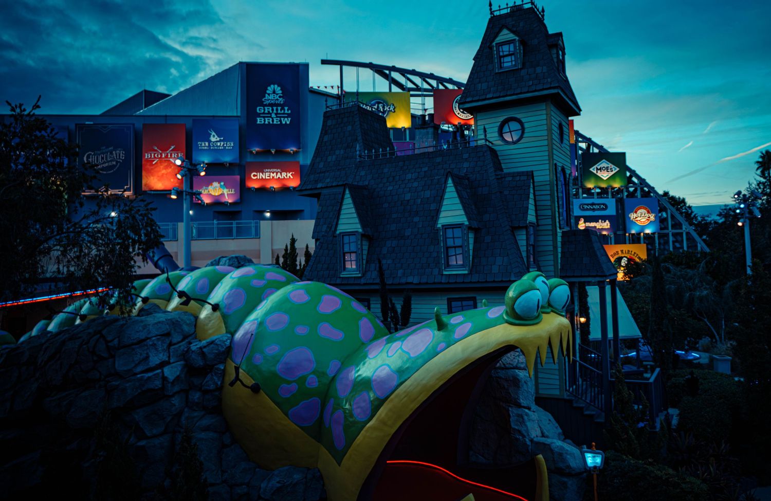 Silhouette of a playground at dusk with dramatic blue sky and buildings in the background.