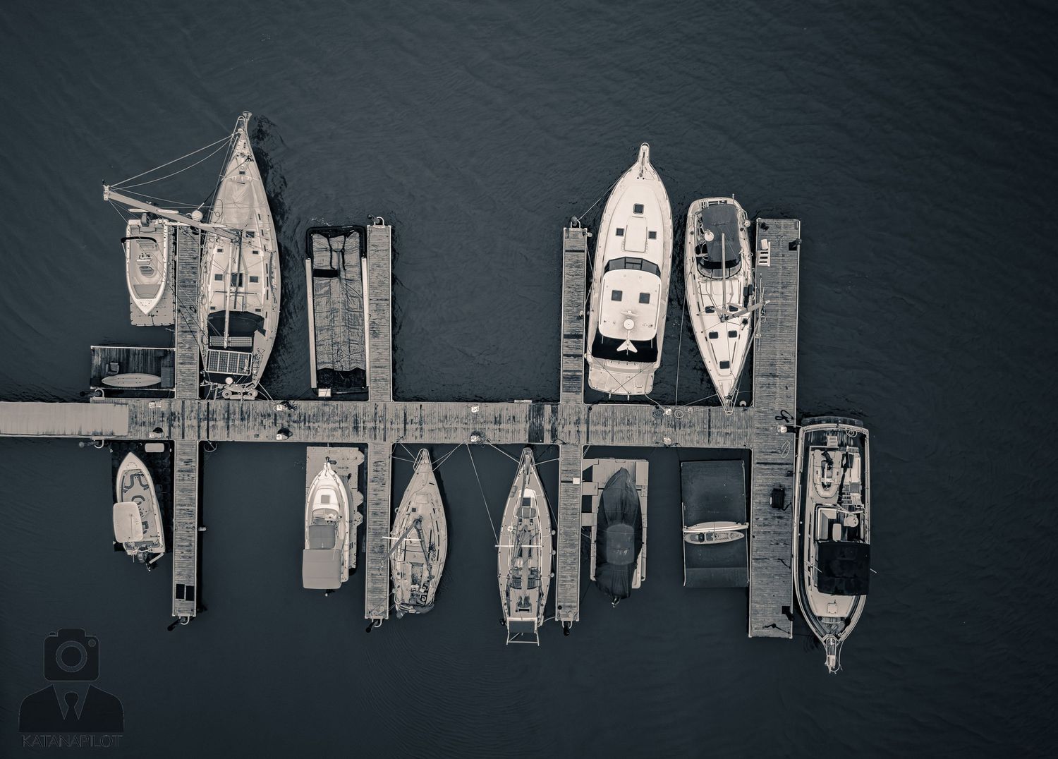 Aerial view of boats and yachts moored at a marina dock captured in a monochromatic style.