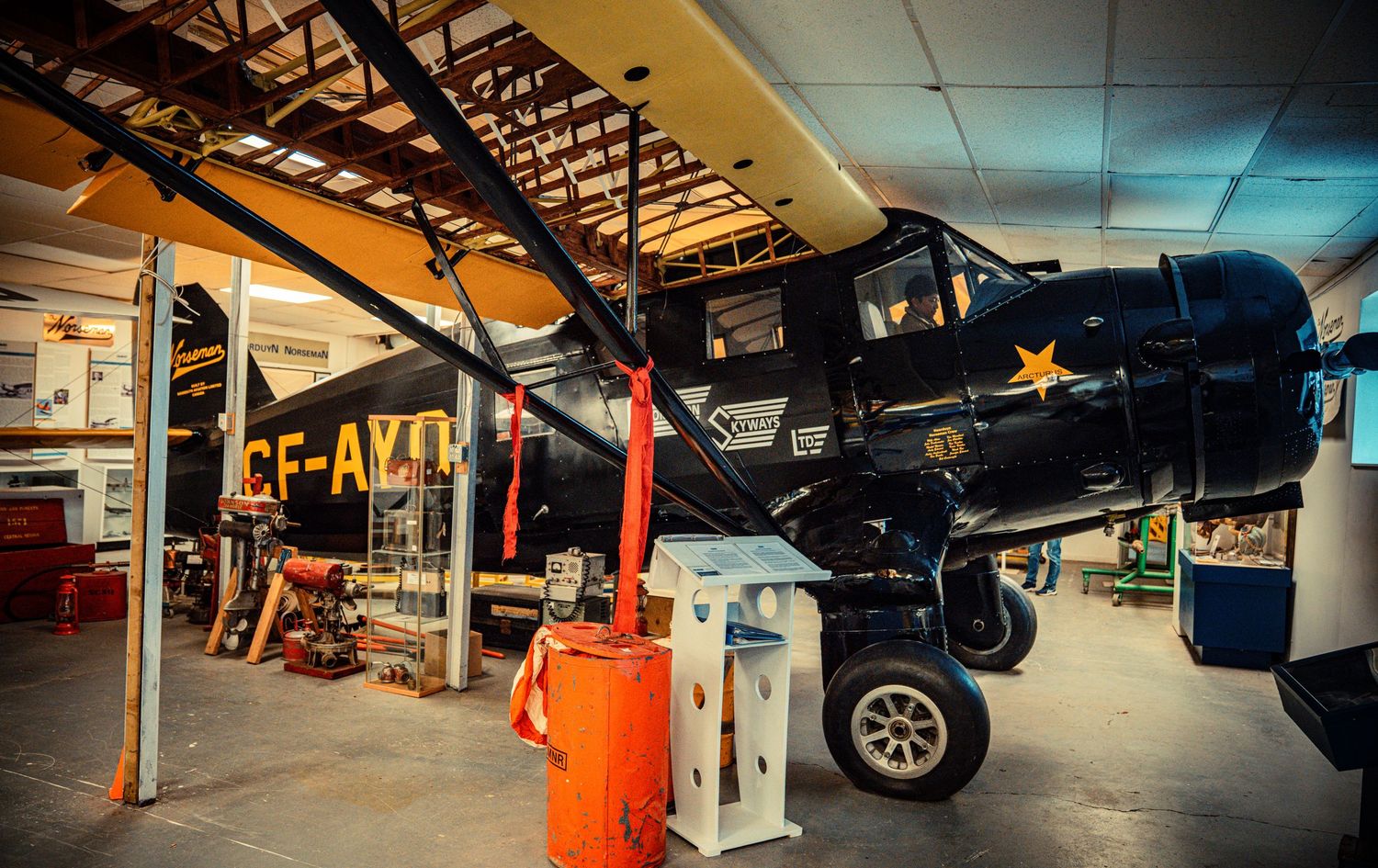 Wide angle shot of a car repair shop interior with orange equipment and multiple vehicle bays.