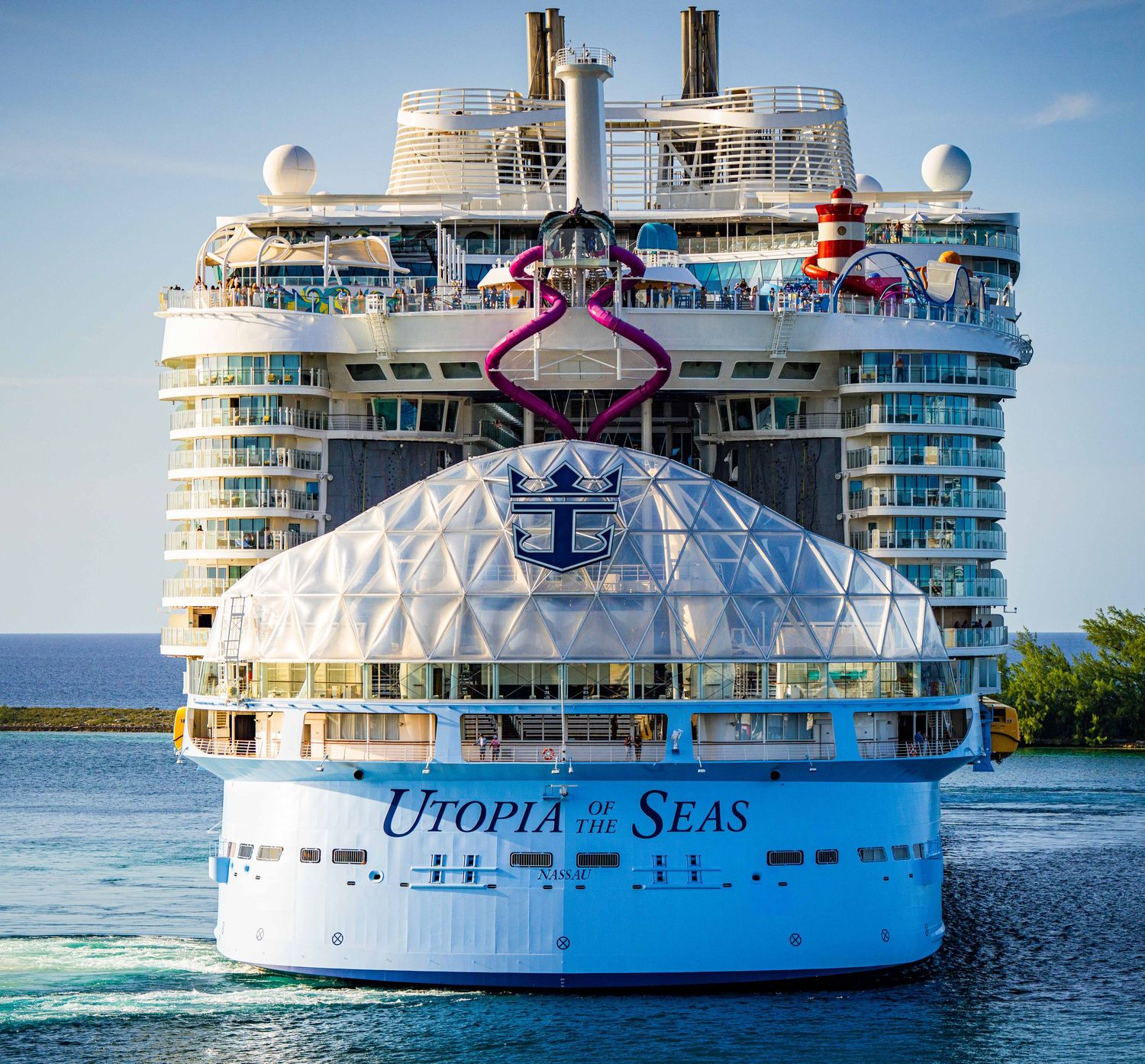 Royal Caribbean's Utopia of the Seas cruise ship stern view docked in port, showcasing its massive white hull and dome.